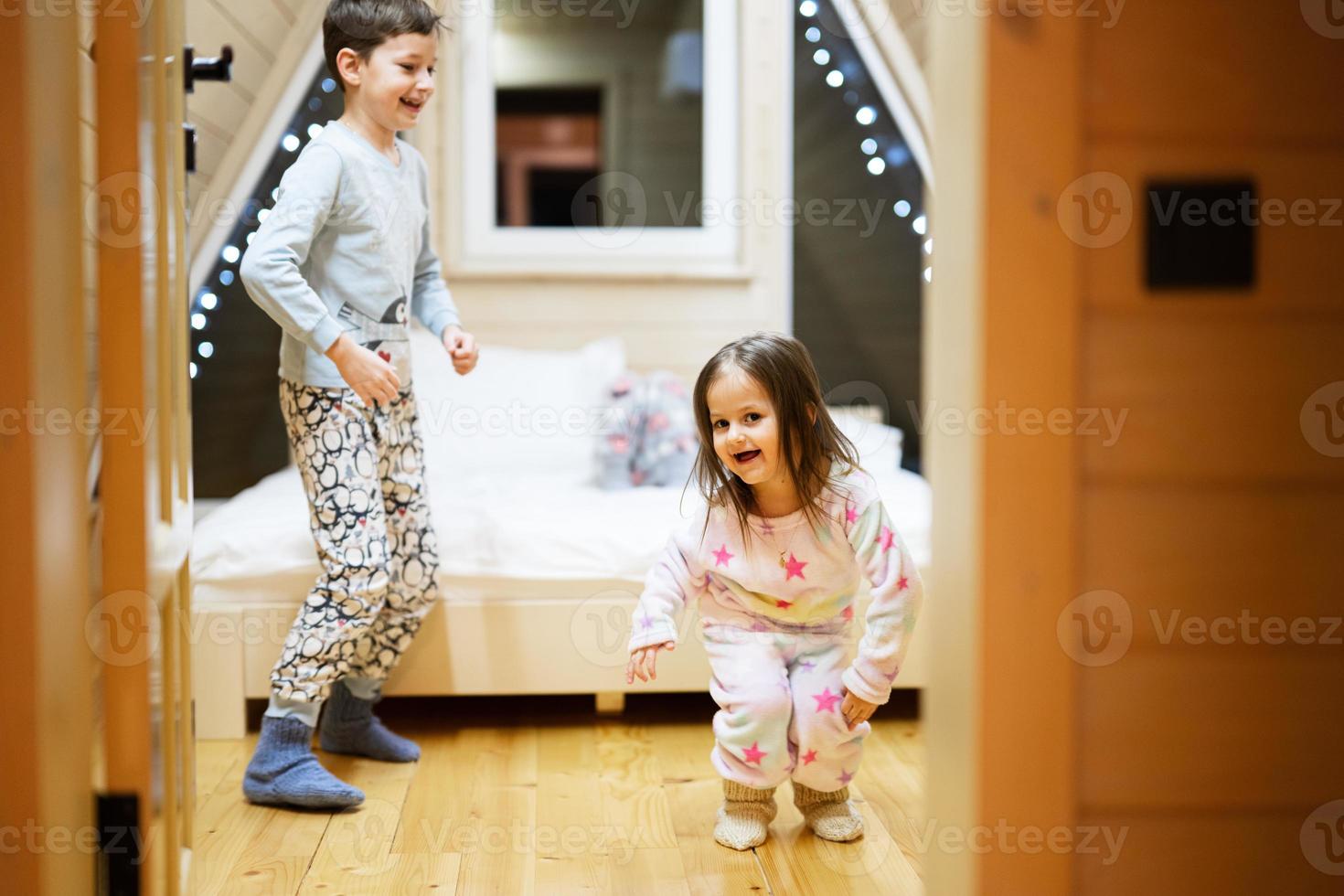 Kinder im Sanft warm Pyjama spielen beim hölzern Kabine heim. Konzept von Kindheit, Freizeit Aktivität, Glück. Bruder und Schwester haben Spaß und spielen zusammen. foto