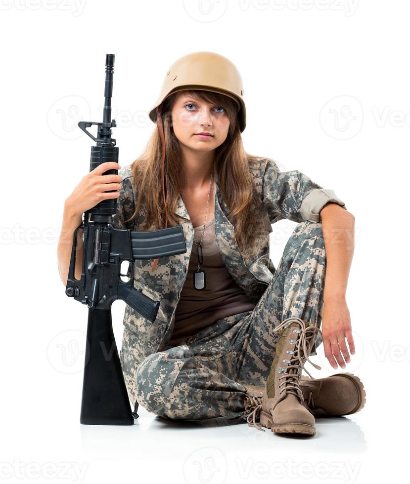 Soldat jung schön Mädchen gekleidet im ein tarnen mit ein Gewehr im seine Hand auf Weiß foto