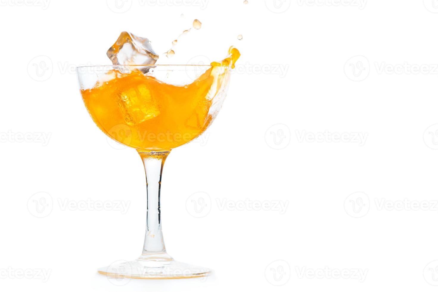 fallen Eis Würfel im zu Orange Limonade im Margarita Glas isoliert foto
