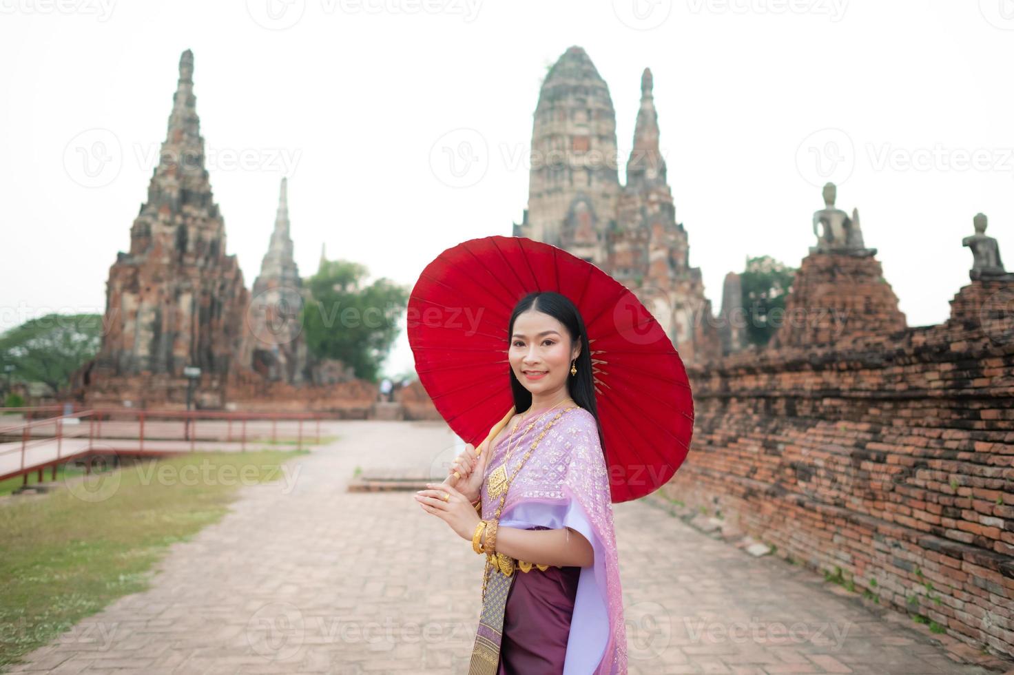 schön thailändisch Mädchen im traditionell Kleid Kostüm rot Regenschirm wie thailändisch Tempel wo ist das Öffentlichkeit Ort, thailändisch Frau im traditionell Kostüm von Thailand. foto