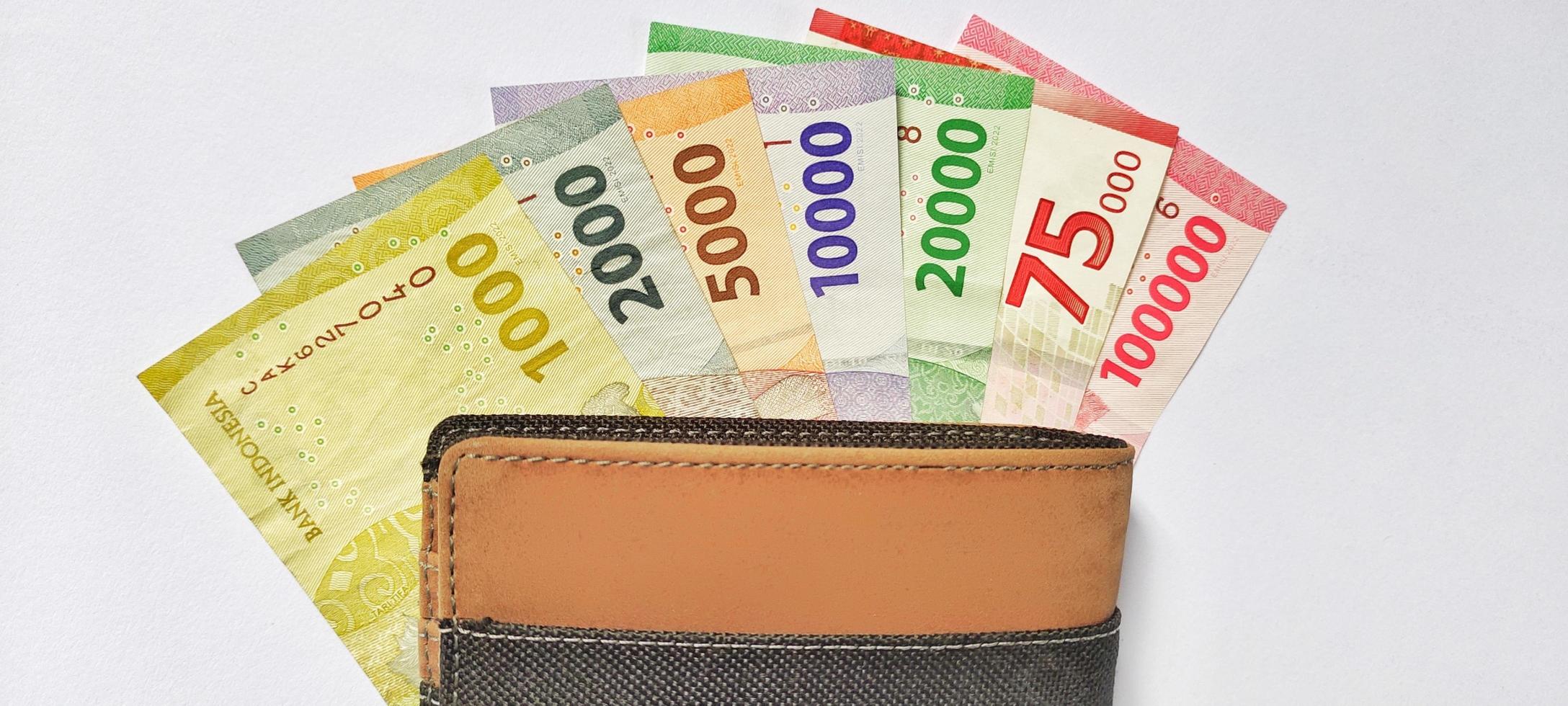 oben Aussicht von ein Brieftasche enthält Neu indonesisch Banknoten problematisch im 2022. Rupiah Währung Konzept isoliert auf ein Weiß Hintergrund. Negativ Raum foto