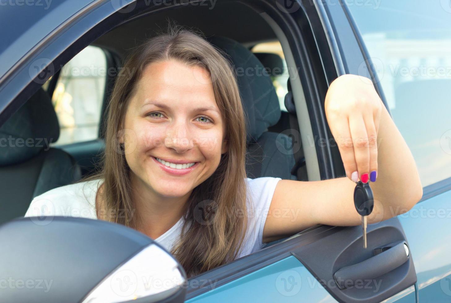 lächelnd jung Mädchen im ein Auto und zeigen Schlüssel foto