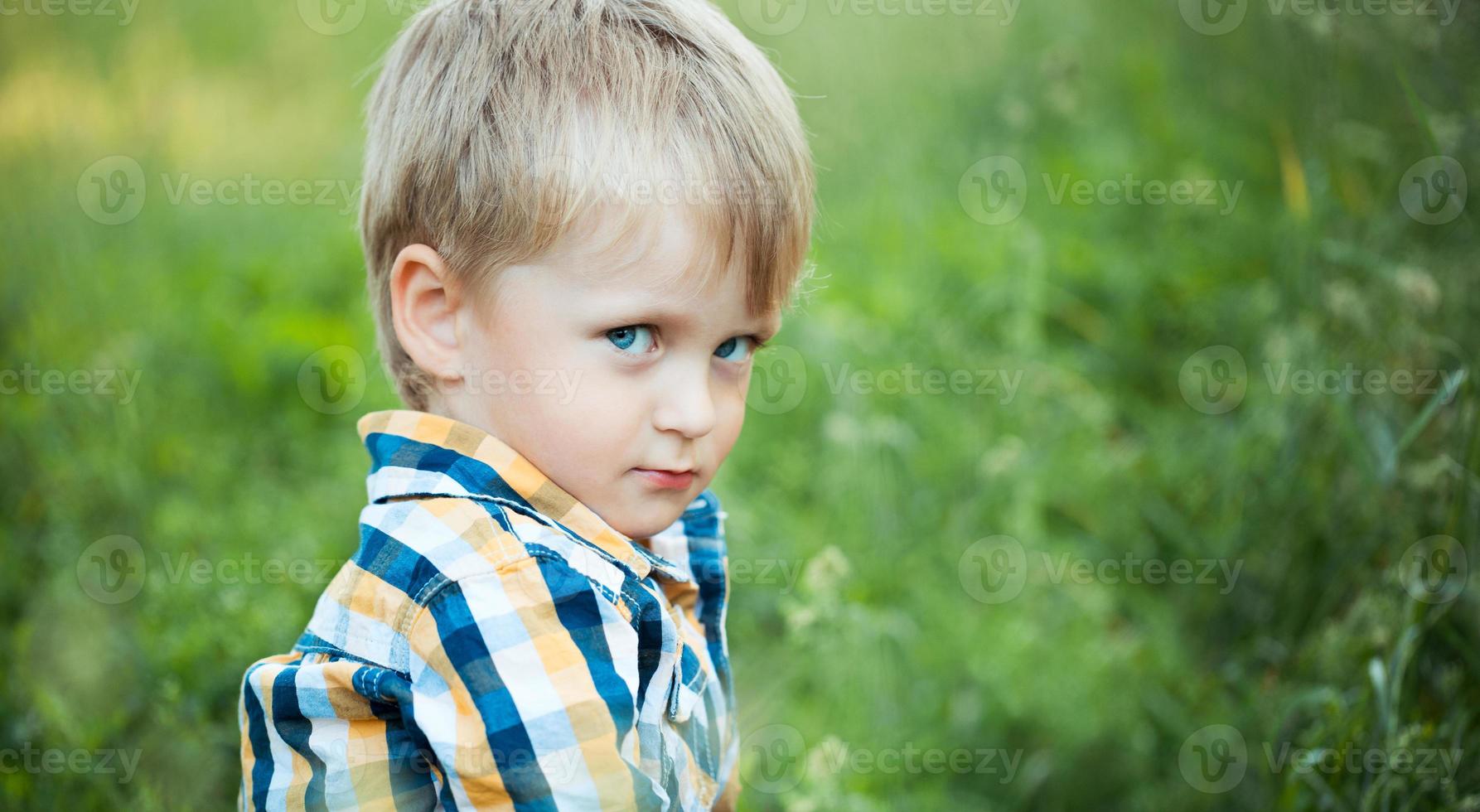 ein süß wenig Baby Junge sitzen im das Gras foto