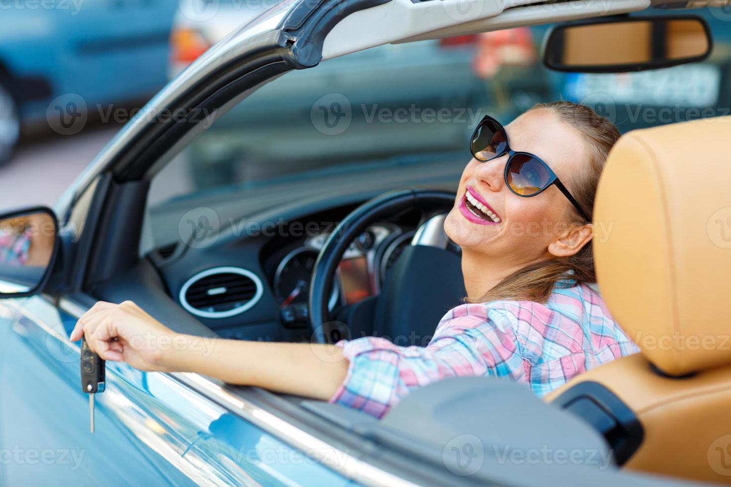 Frau im Sonnenbrille Sitzung im ein Cabrio Auto mit das Schlüssel im Hand - - Konzept von Kauf ein benutzt Auto oder ein Vermietung Auto foto