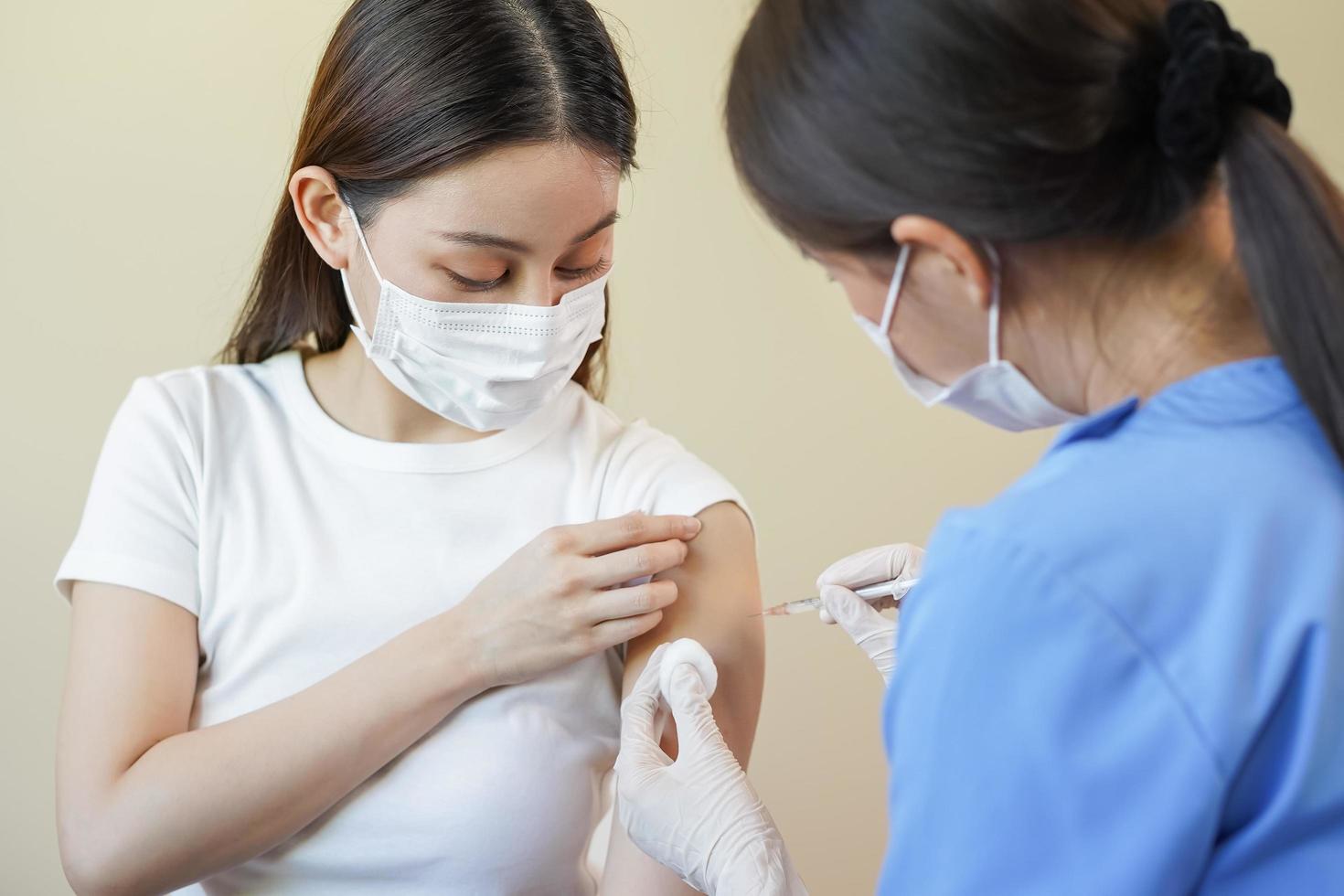 Covid-19, Coronavirus Hand von jung Frau Krankenschwester, Arzt geben Spritze Impfung, injizieren Schuss zu asiatisch Waffen geduldig. Impfung, Immunisierung oder Krankheit Verhütung gegen Grippe oder Virus Pandemie Konzept. foto