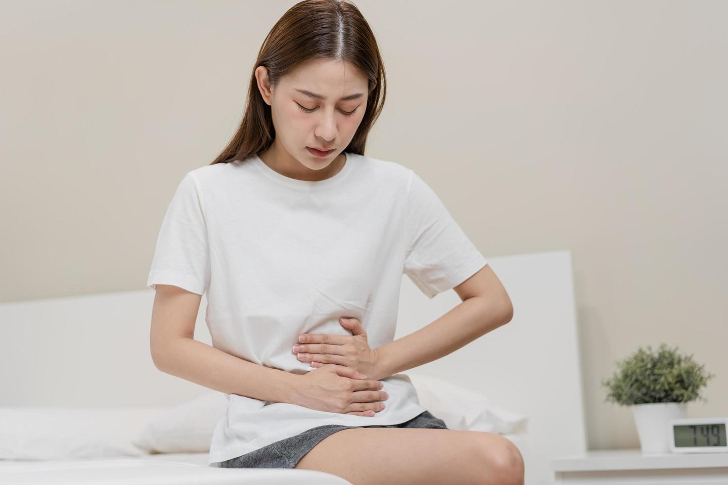 Blähung Geschwür, asiatisch jung Frau, Mädchen Hände im Bauch, Magenschmerzen von Essen Vergiftung, Bauch Schmerzen und Verdauungs- Problem, Gastritis oder Durchfall. Abdomen Entzündung, Menstruation- Zeitraum Personen. foto