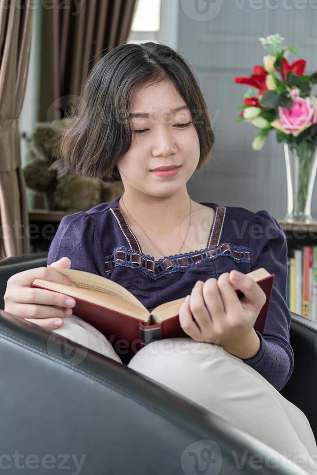 junge asiatische frau mit kurzen haaren las ein buch im wohnzimmer foto