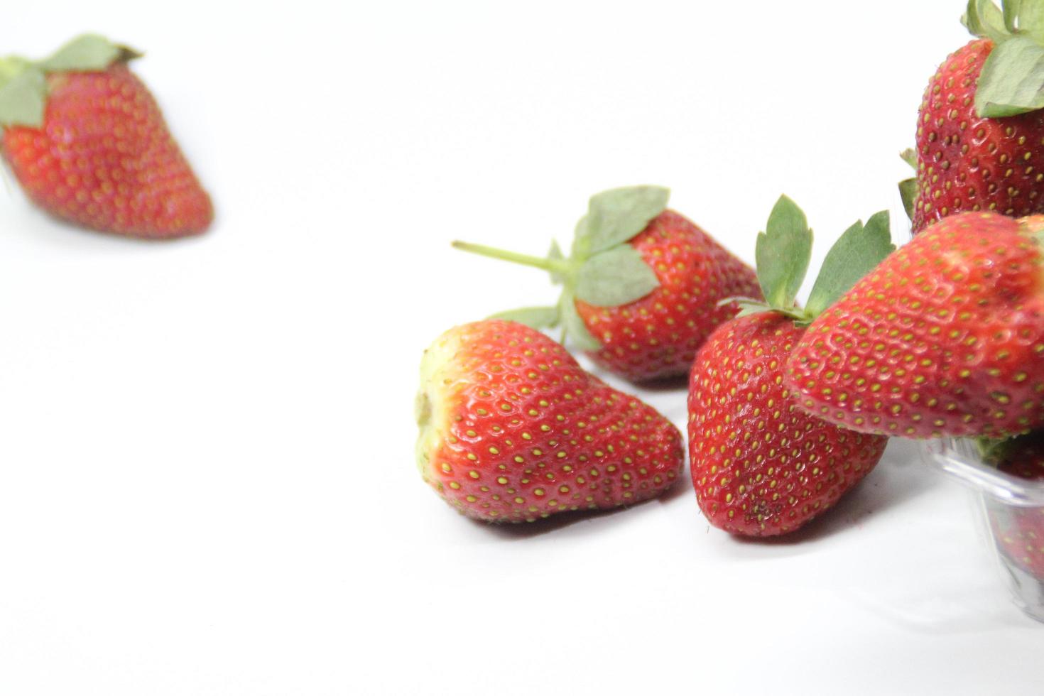 Erdbeeren in einem Plastikbehälter auf einem weißen Hintergrund foto