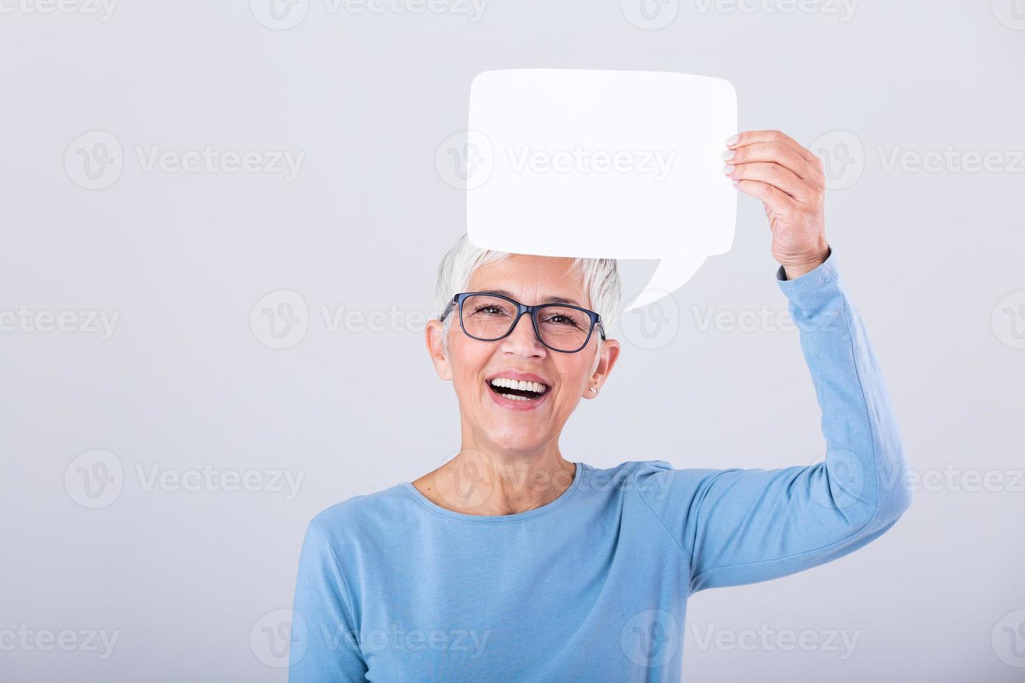 Porträt von ein ein aufgeregt reifen grau Haar Frau zeigen leer Rede Blase isoliert Über grau Hintergrund. Senior Frau halten Rede Blase Banner foto