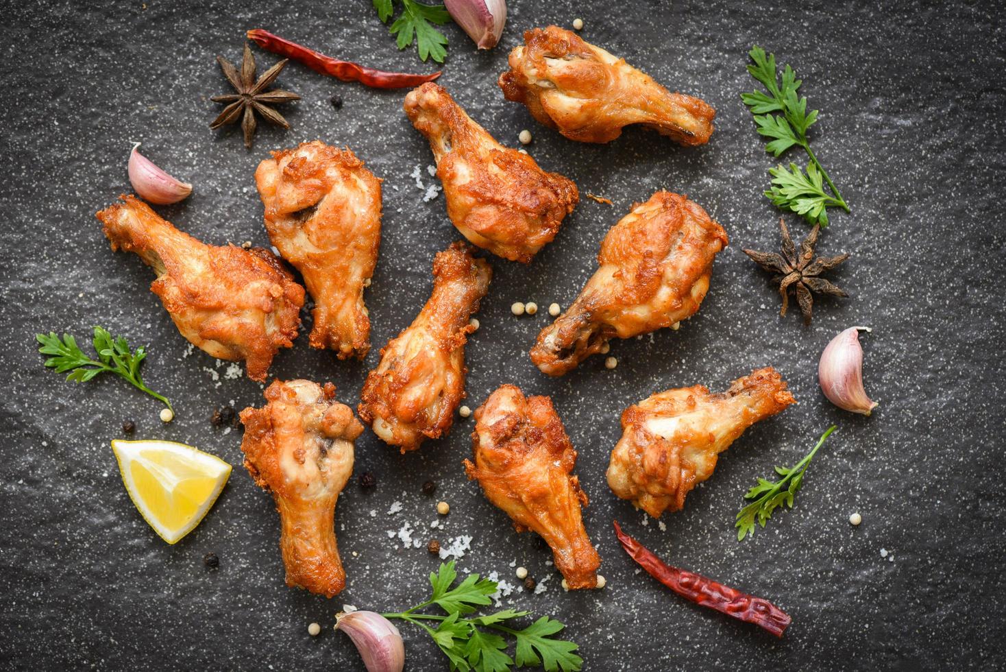 gebraten Hähnchen Flügel mit Zitrone Knoblauch Chili Kräuter und Gewürze auf schwarz Teller oben Aussicht - - gebacken Hähnchen Flügel Grill foto