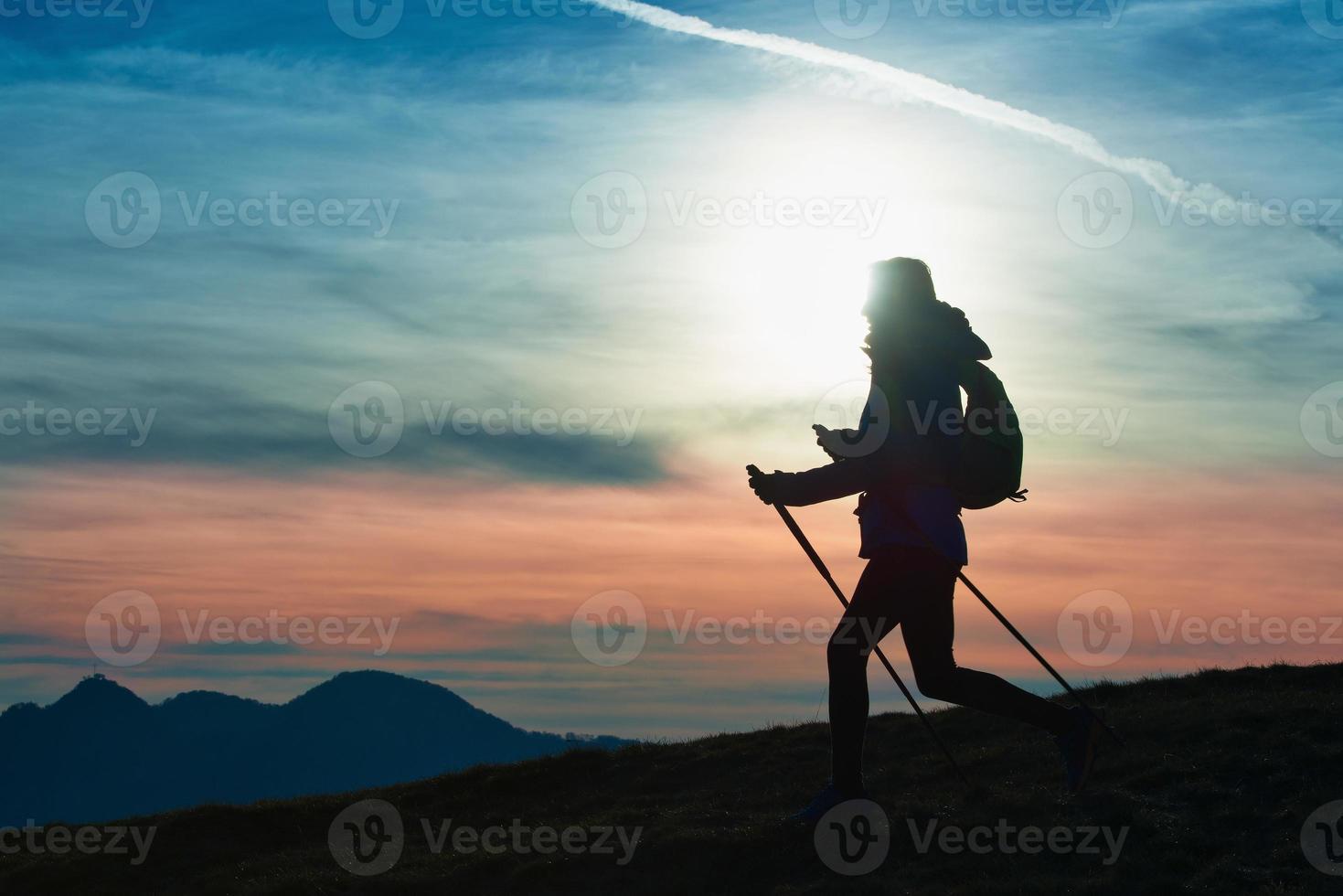 Silhouette eines Mädchens auf einem Berg während einer religiösen Wanderung in einem blauen und orangefarbenen Himmel. foto