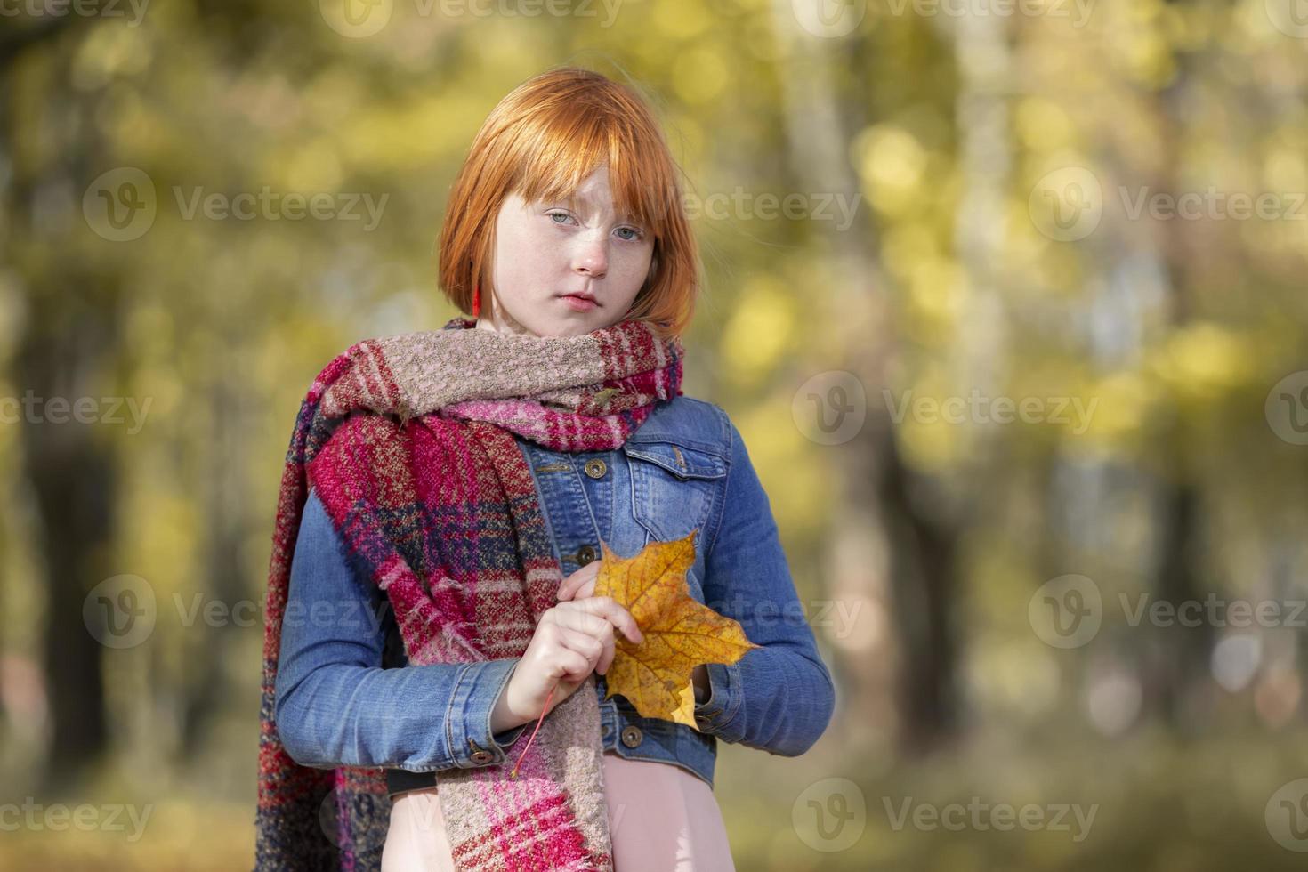 traurig nachdenklich rothaarig Mädchen mit ein Ahorn Blatt im das Herbst Park. foto