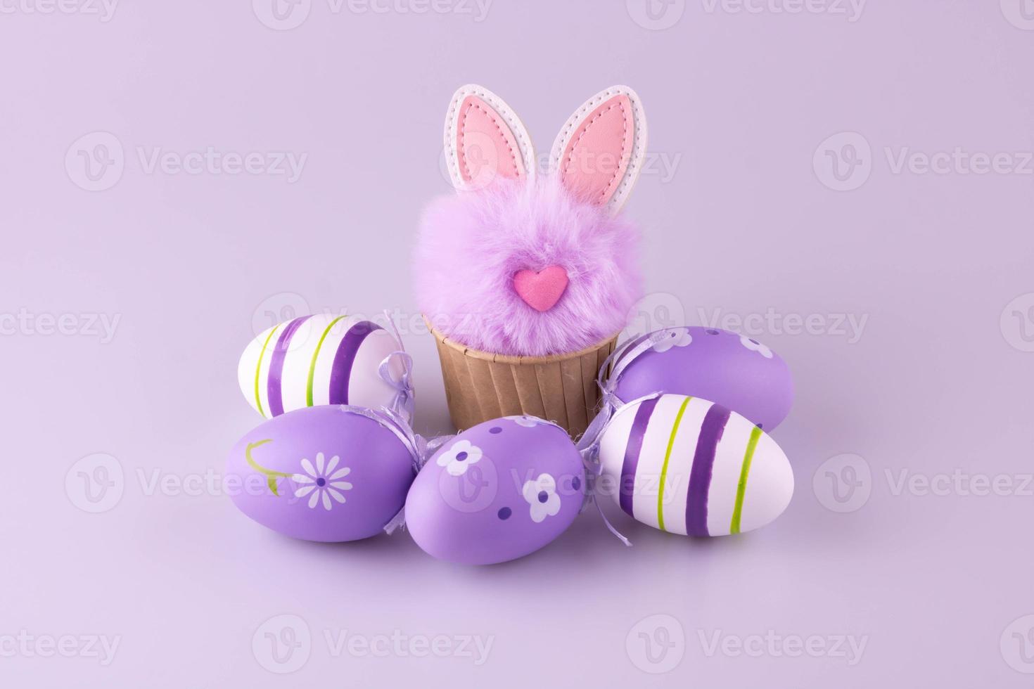 lila flauschige Spielzeug Hase im ein Cupcake Backen Gericht, Ostern Eier sind Lügen Nächster zu Es. foto