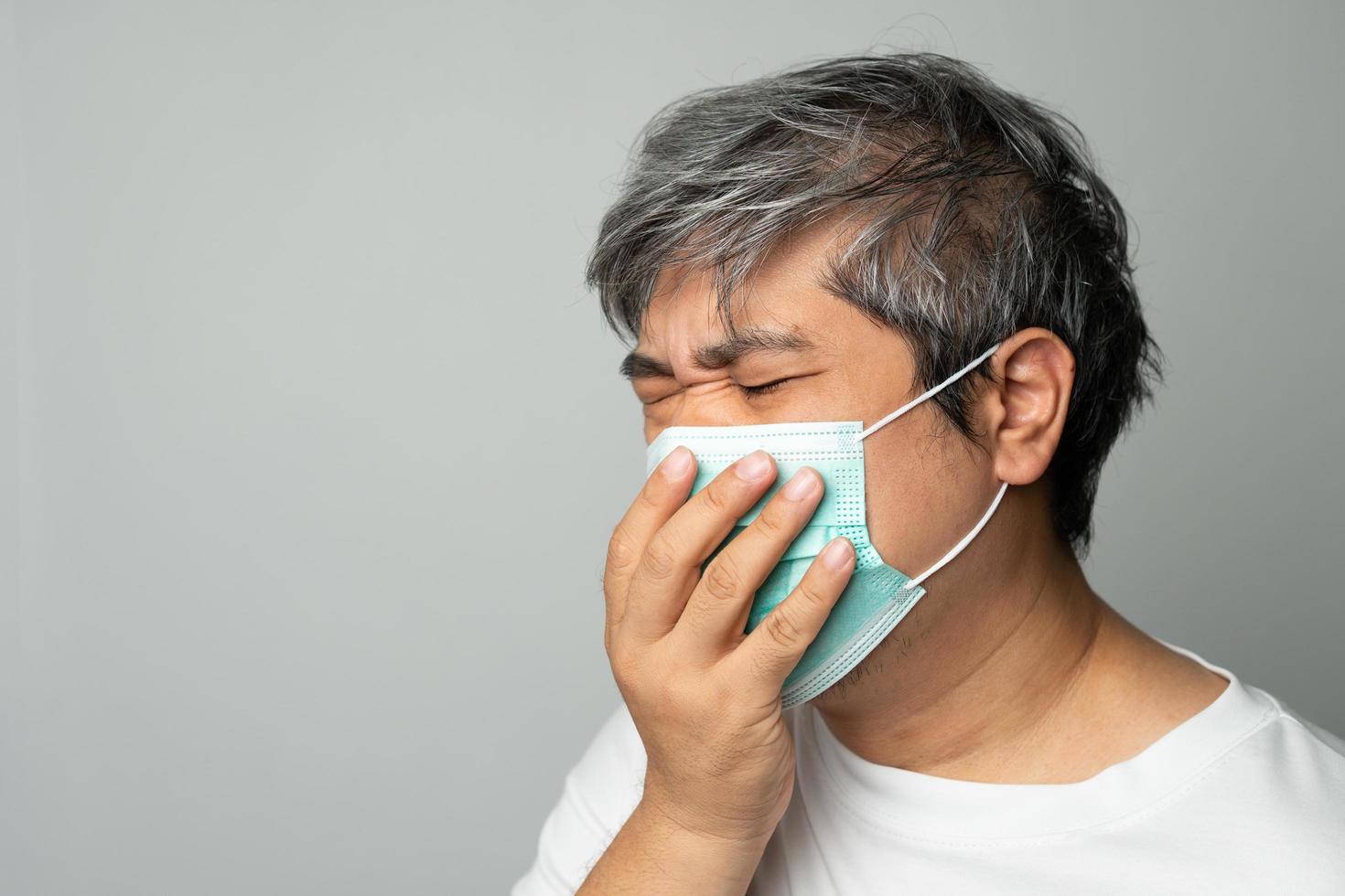 kranker asiatischer mann, der eine medizinische gesichtsmaske trägt und hustet und seinen mund mit meiner hand bedeckt. konzept des schutzes pandemie coronavirus und atemwegserkrankungen foto