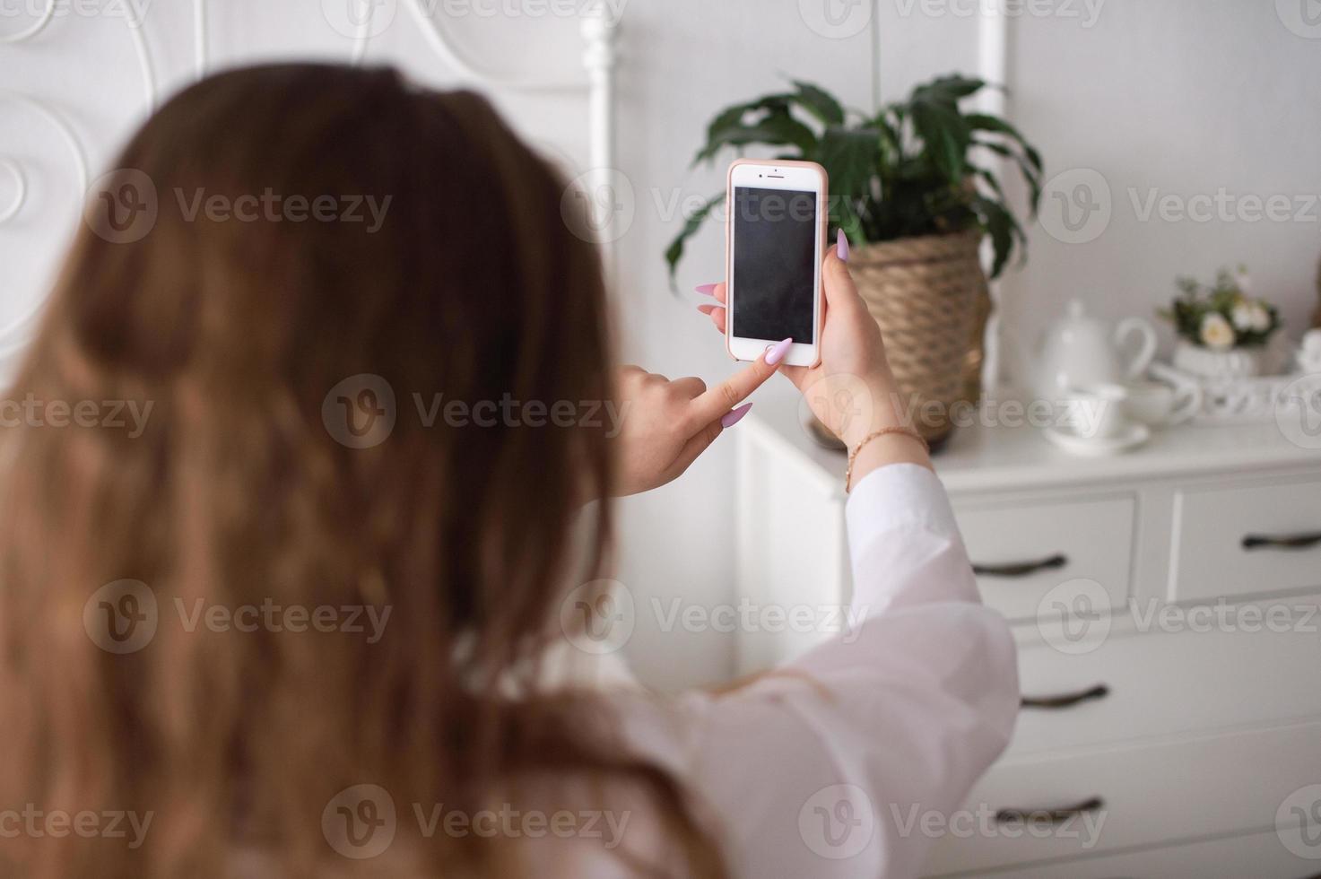 ein jung emotional Frau drückt das Telefon Taste. ohne ein Gesicht foto