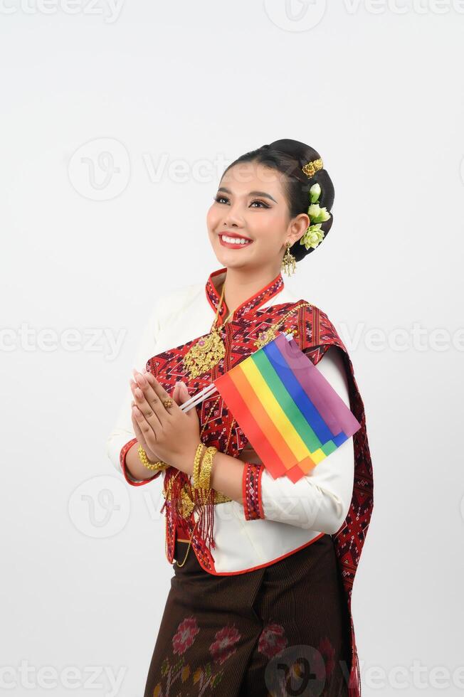 Porträt von jung Frau im thailändisch nordöstlich traditionell Kleidung halten Regenbogen Flagge foto