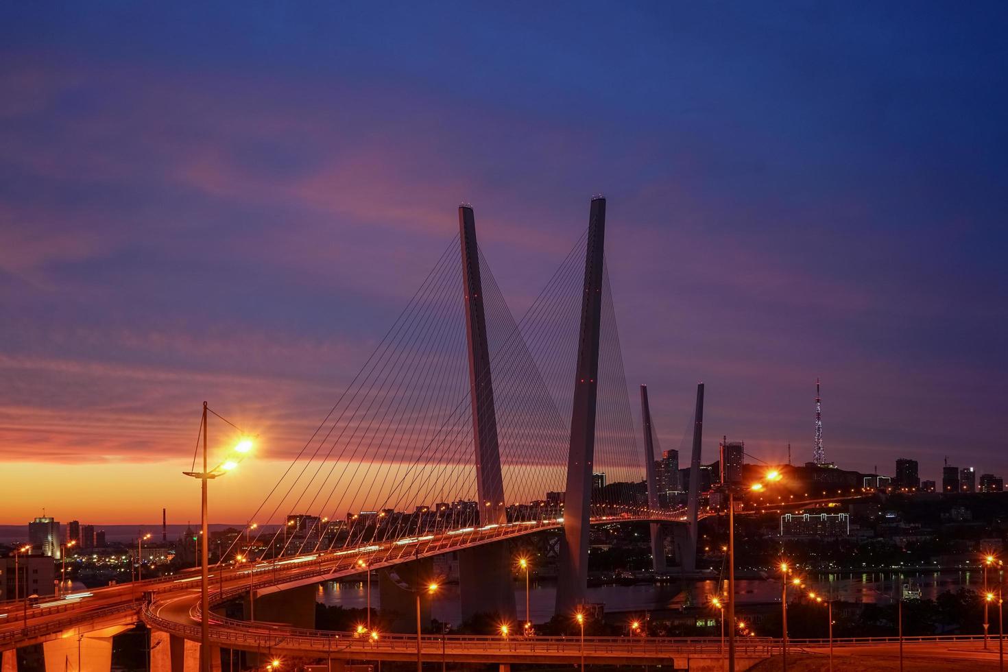 goldene Brücke mit buntem Sonnenuntergangsonnenuntergang in Wladiwostok, Russland foto