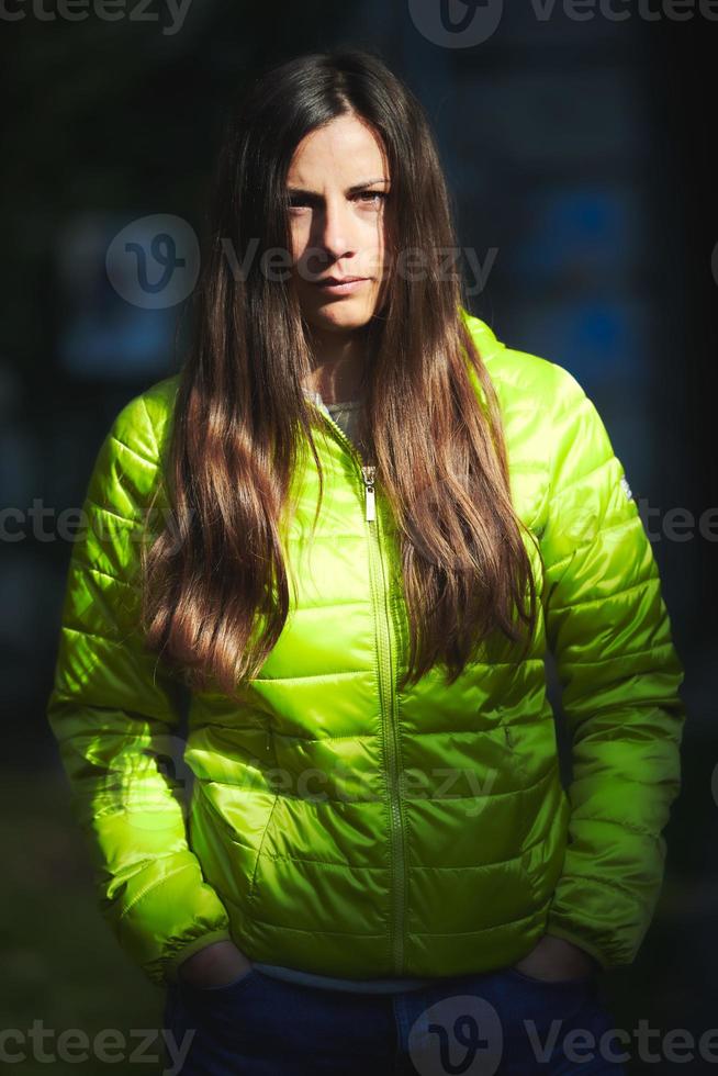 Porträt eines schönen kaukasischen Mädchens mit langen braunen Haaren mit grüner Winterjacke foto