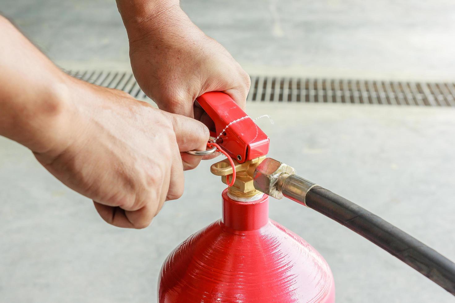 männliche Hände ziehen Sicherheitsnadel des Feuerlöschers Nahaufnahme foto