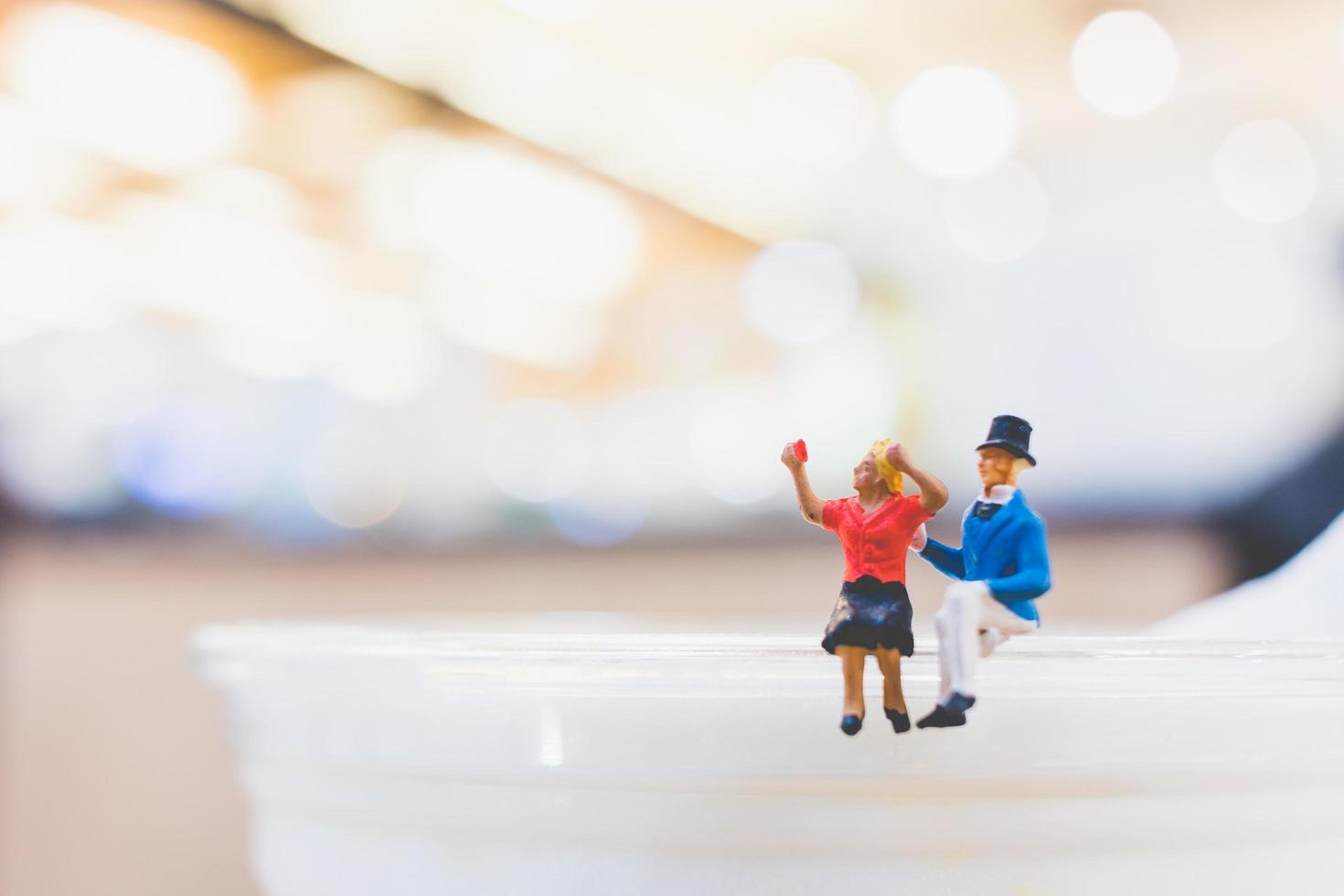 Miniaturpaar sitzt auf einer Tasse, Valentinstagskonzept foto