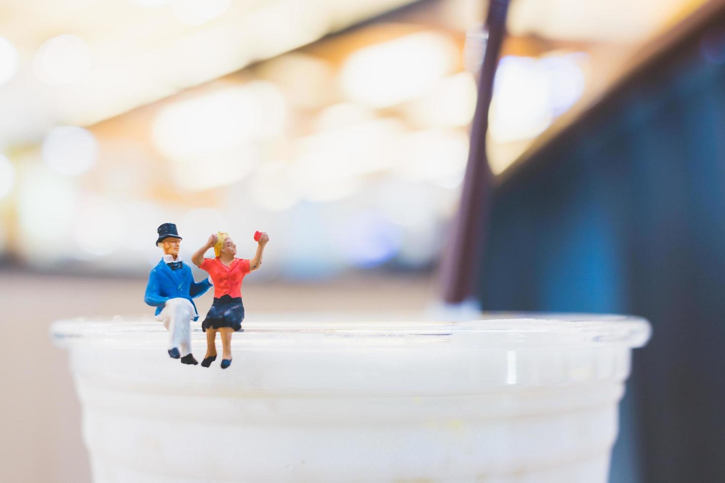 Miniaturpaar sitzt auf einer Tasse, Valentinstagskonzept foto