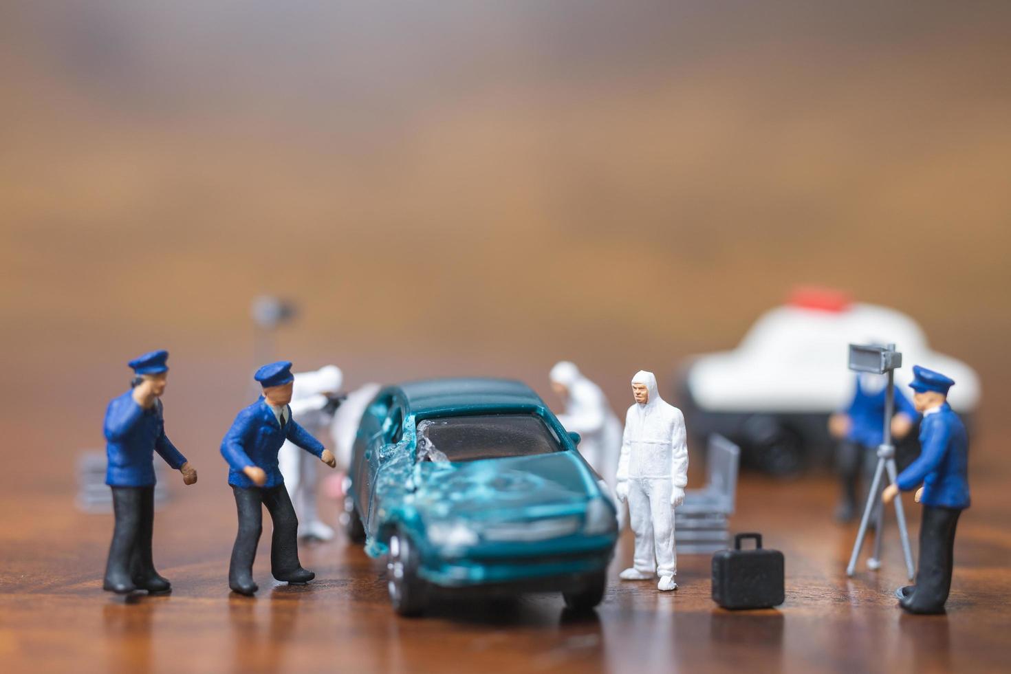 Miniaturpolizei und Detektiv, die um ein Auto stehen, Tatortuntersuchungskonzept foto