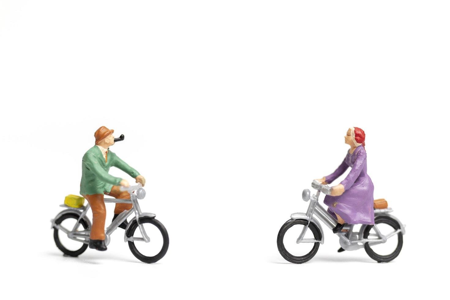 Miniaturpaar, das Fahrräder auf einem weißen Hintergrund reitet, Valentinstagkonzept foto