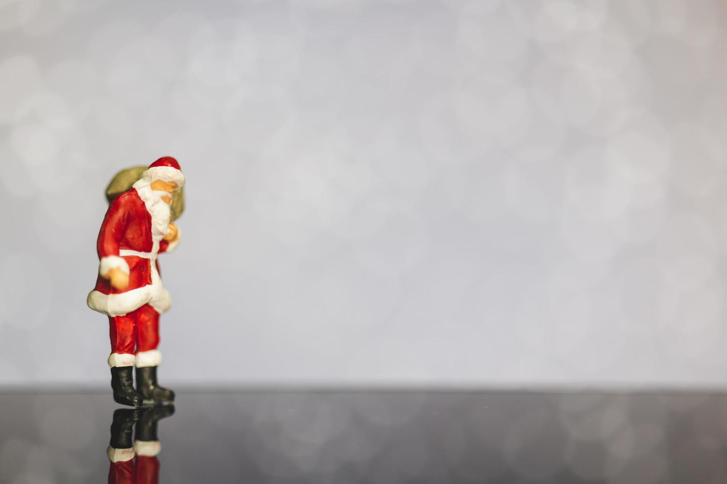 Miniatur-Weihnachtsmann, der eine Tasche auf einem Bokeh-Hintergrund, frohe Weihnachten und ein frohes neues Jahr-Konzept trägt. foto