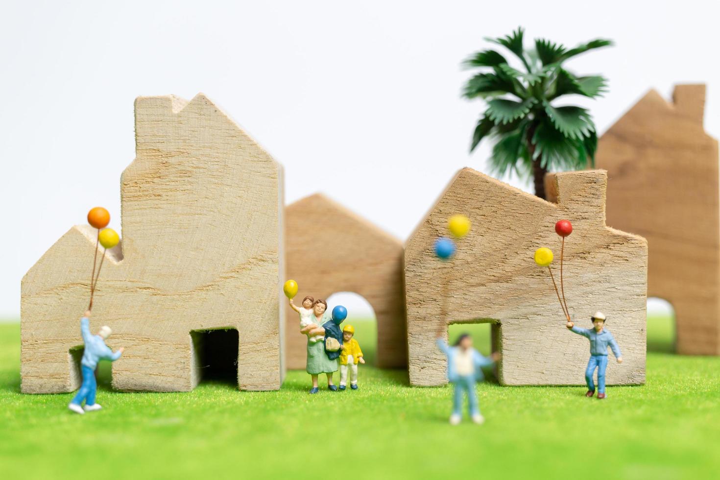 Miniaturfamilie, die in einem Feld mit Luftballons, glücklichen Familienbeziehungen und sorglosem Freizeitkonzept geht foto