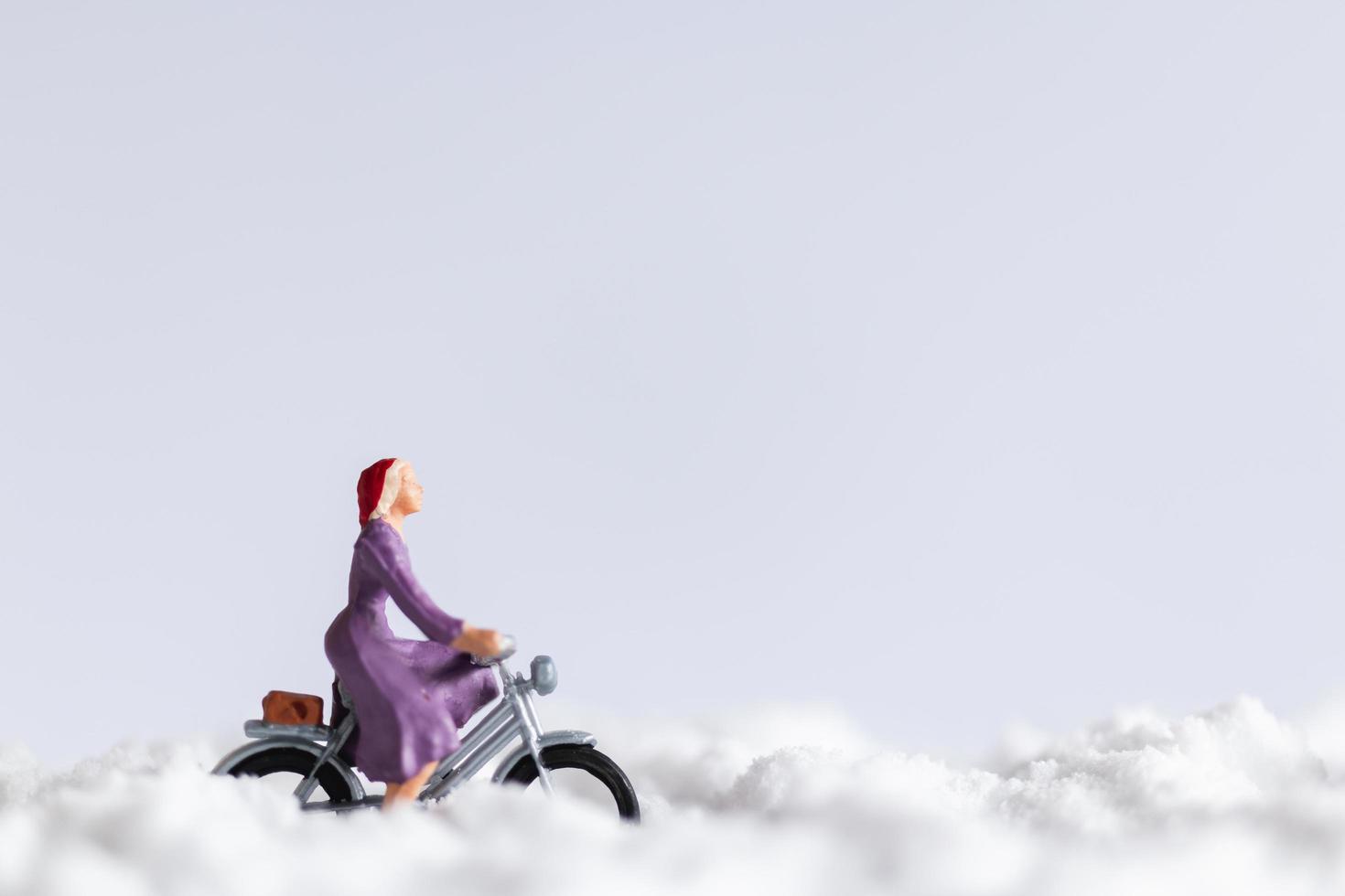 Miniaturreisende, die Fahrräder im Schnee, Winterhintergrundkonzept reiten foto