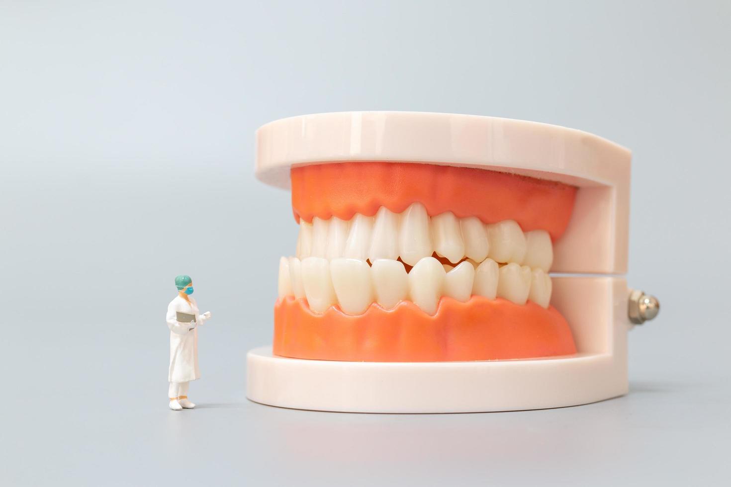 Miniaturzahnarzt, der menschliche Zähne mit Zahnfleisch und Zahnschmelz repariert, Gesundheits- und medizinisches Konzept foto