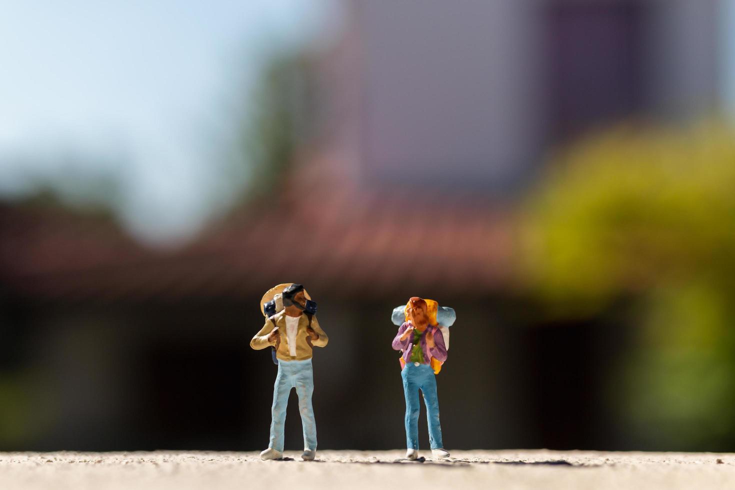 Miniaturreisende mit Rucksäcken, die auf einer Straße stehen, Reisekonzept foto