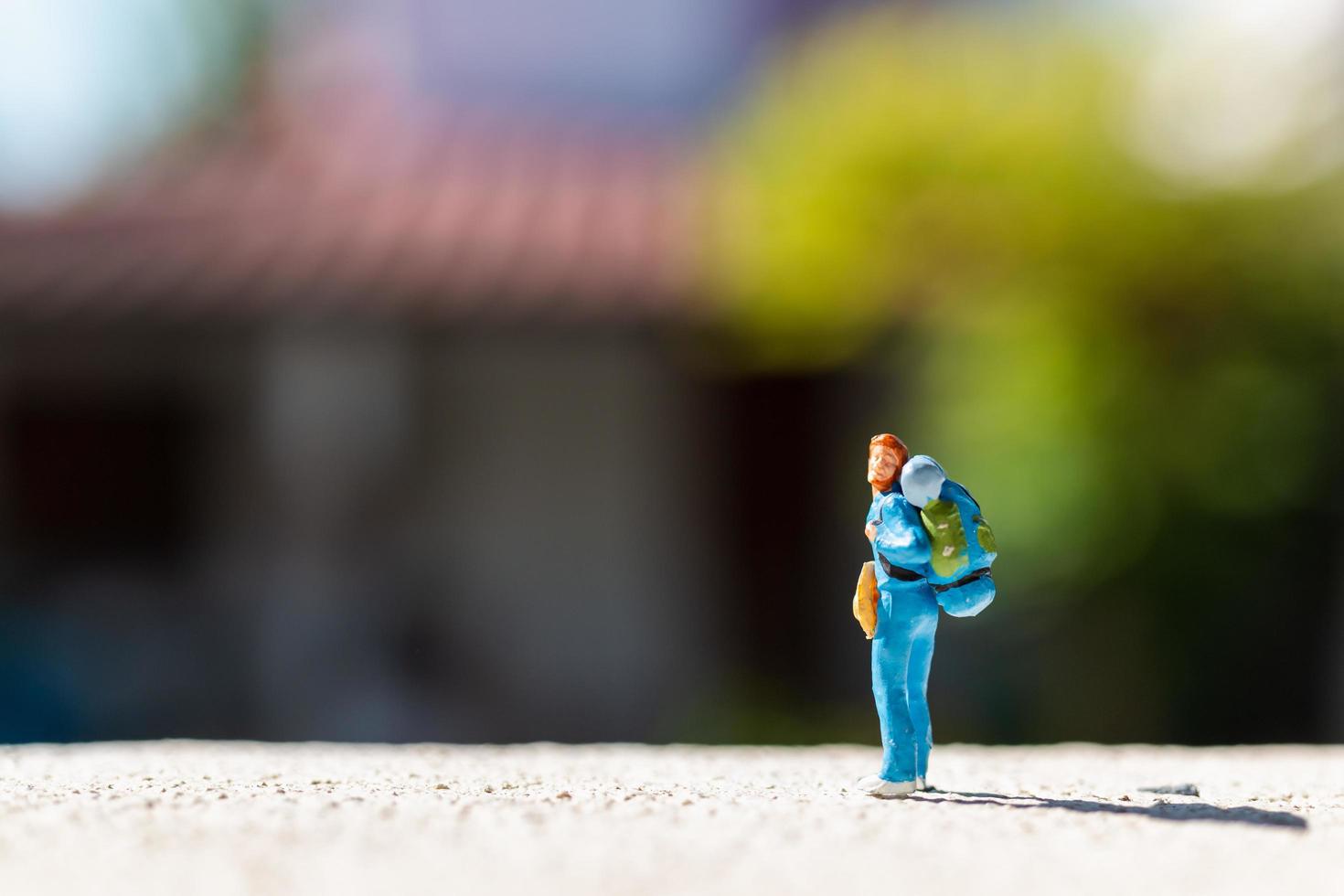 Miniaturreisender mit einem auf einer Straße stehenden Rucksack, Reisekonzept foto