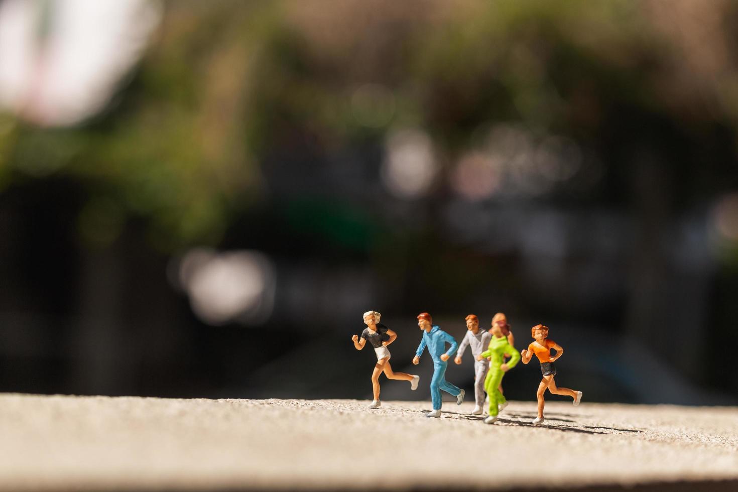 Miniaturgruppe von Menschen, die auf einer konkreten Straße laufen, gesundes Lebensstilkonzept foto