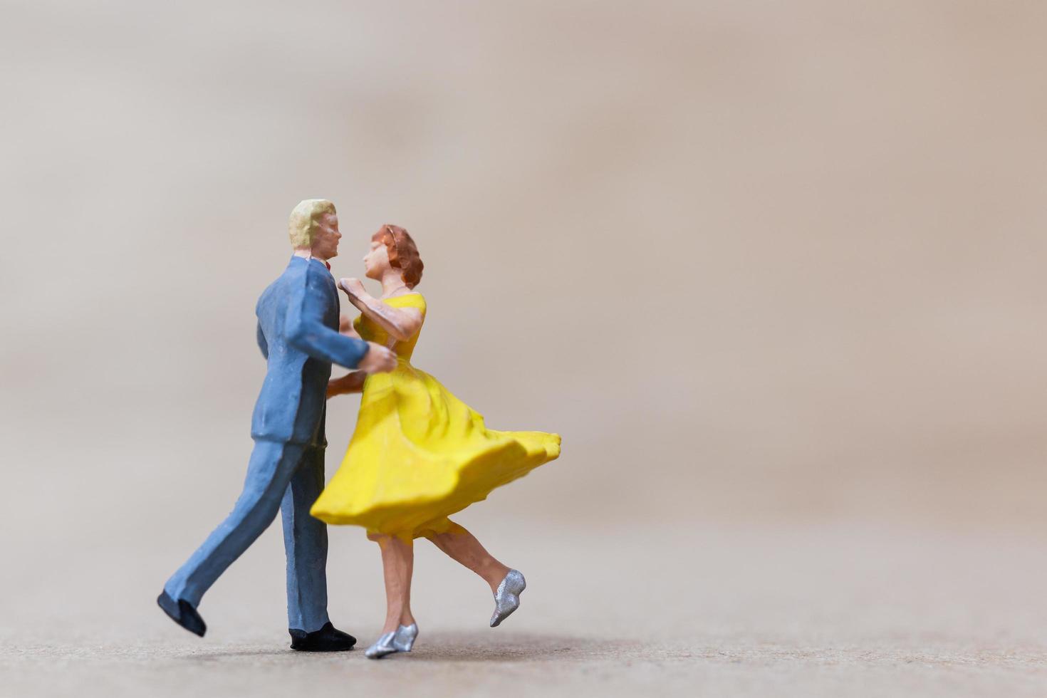Miniaturpaar tanzt auf einem hölzernen Hintergrund, Valentinstagkonzept foto