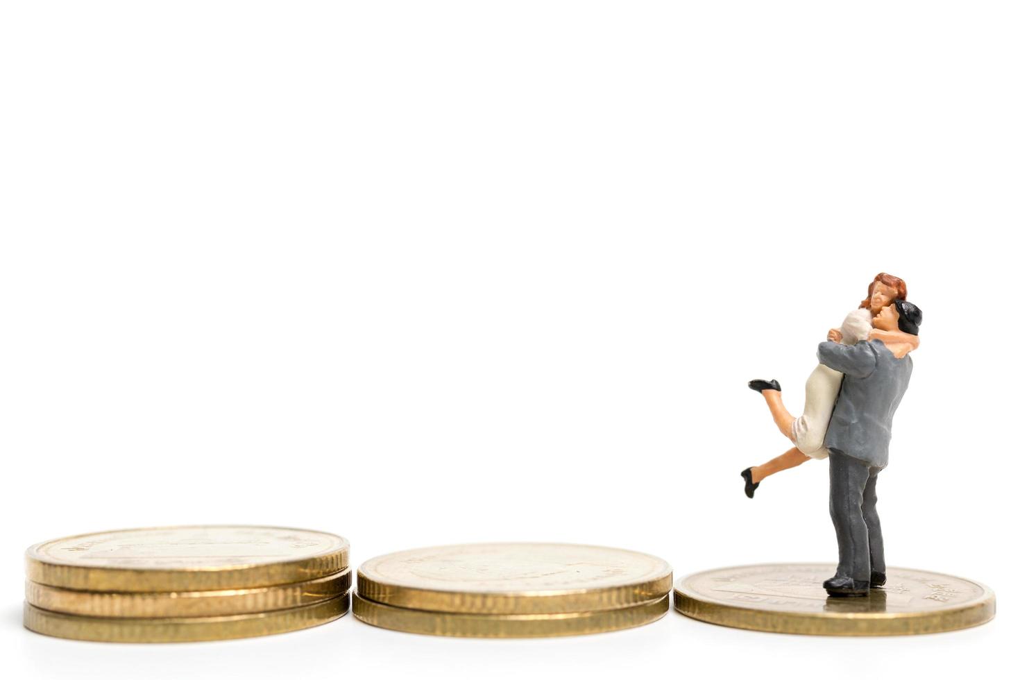 Miniaturpaar umarmt einen Stapel Münzen, Geld und Finanzkonzept foto