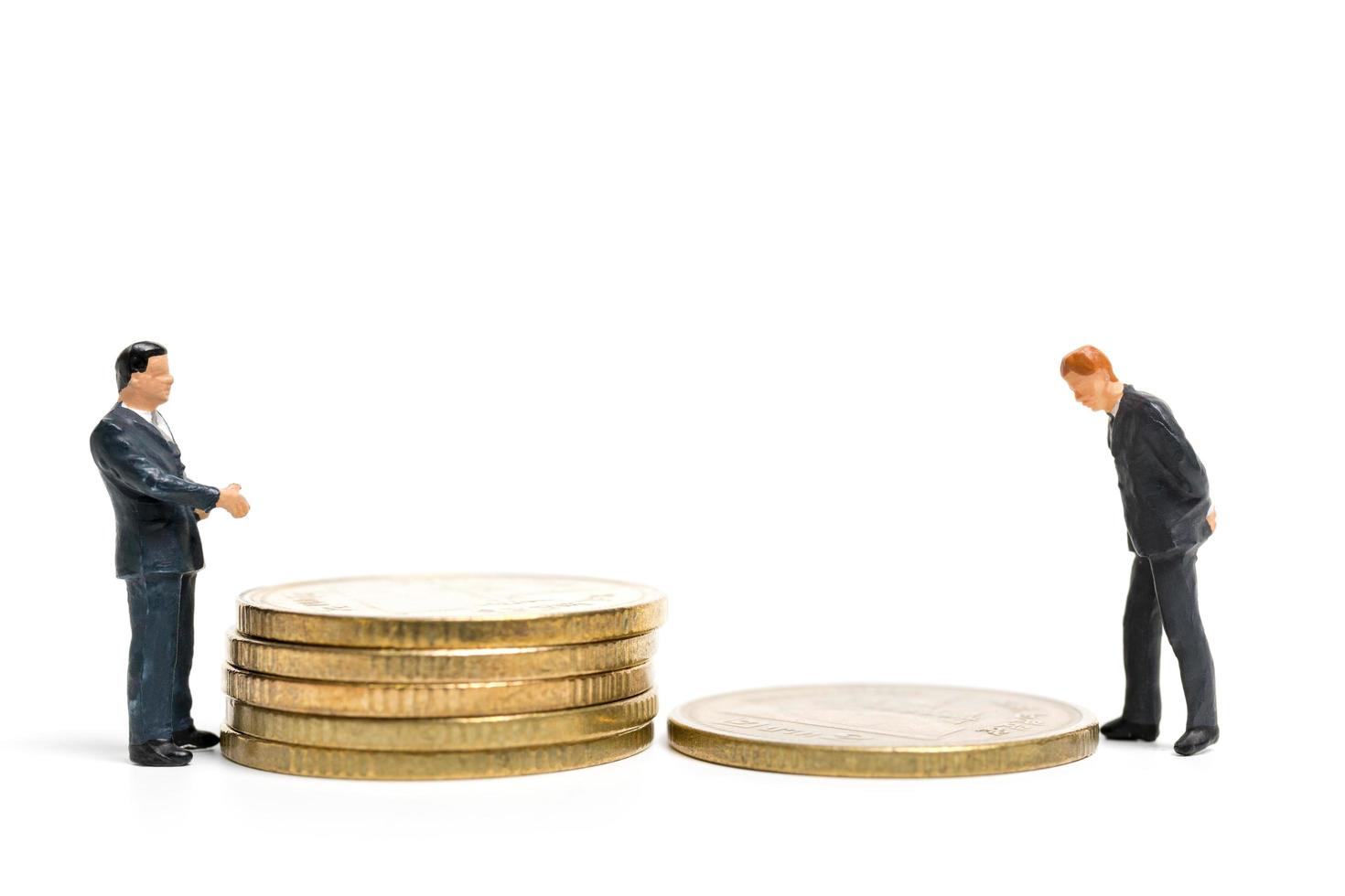 Miniaturgeschäftsleute, die auf einem Stapel von Münzen, Geld und Finanzkonzept stehen foto