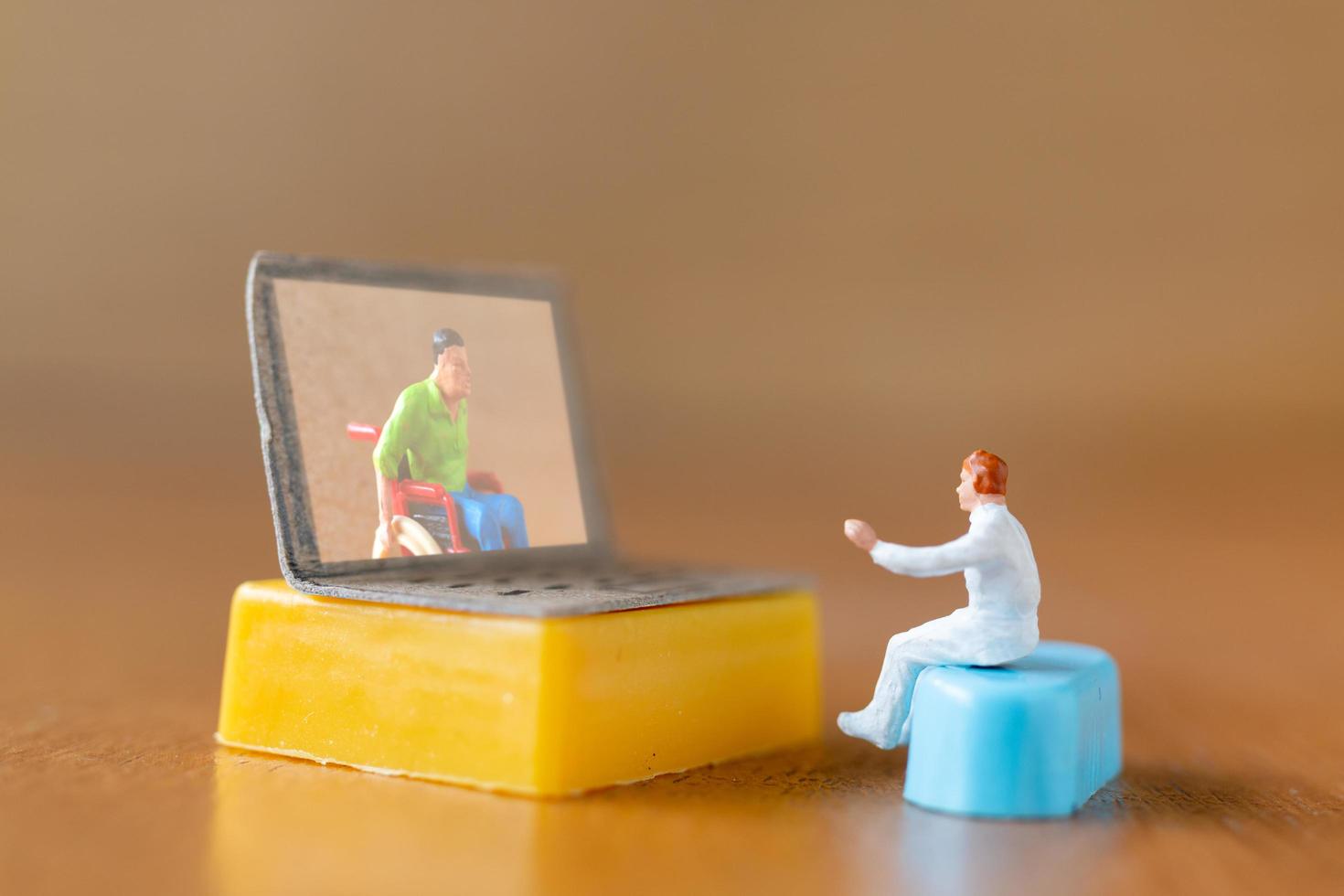Beratung eines männlichen Miniaturpatienten mit einem Arzt unter Verwendung eines Videoanrufs auf einem Laptop, Online-Arztkonzept foto