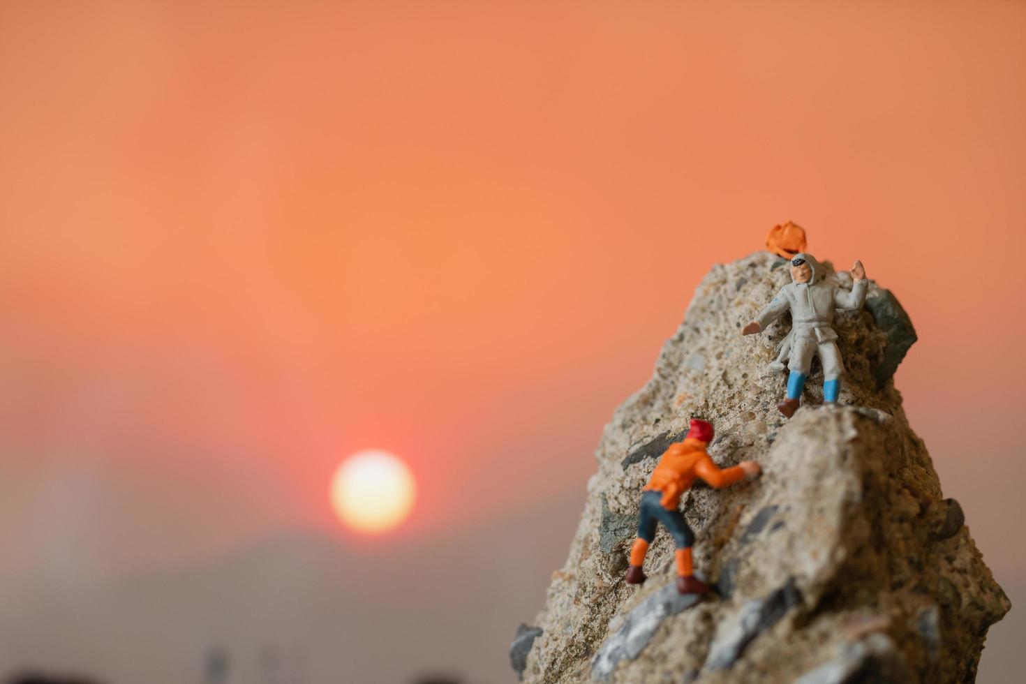 Miniaturwanderer, die auf ein Felsen-, Sport- und Freizeitkonzept klettern foto