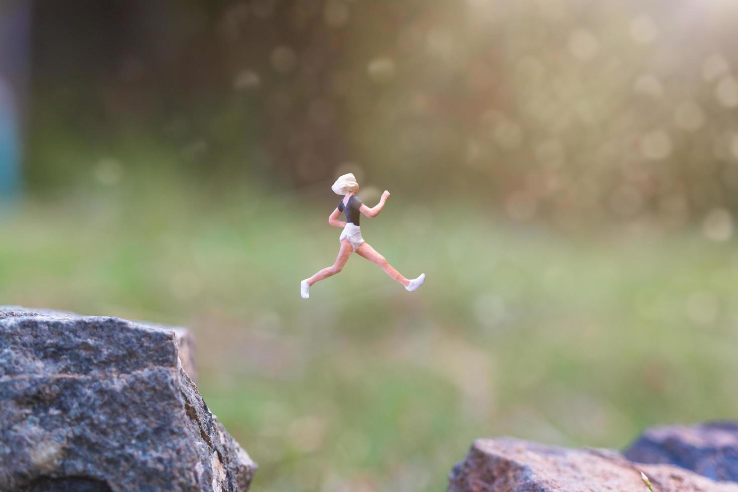 Miniaturmenschen, die auf einer Felsenklippe mit Naturhintergrund-, Gesundheits- und Lebensstilkonzept laufen foto
