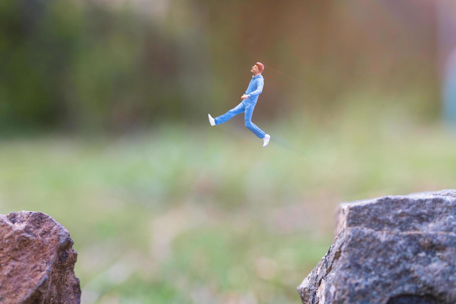Miniaturmenschen, die auf einer Felsenklippe mit Naturhintergrund-, Gesundheits- und Lebensstilkonzept laufen foto
