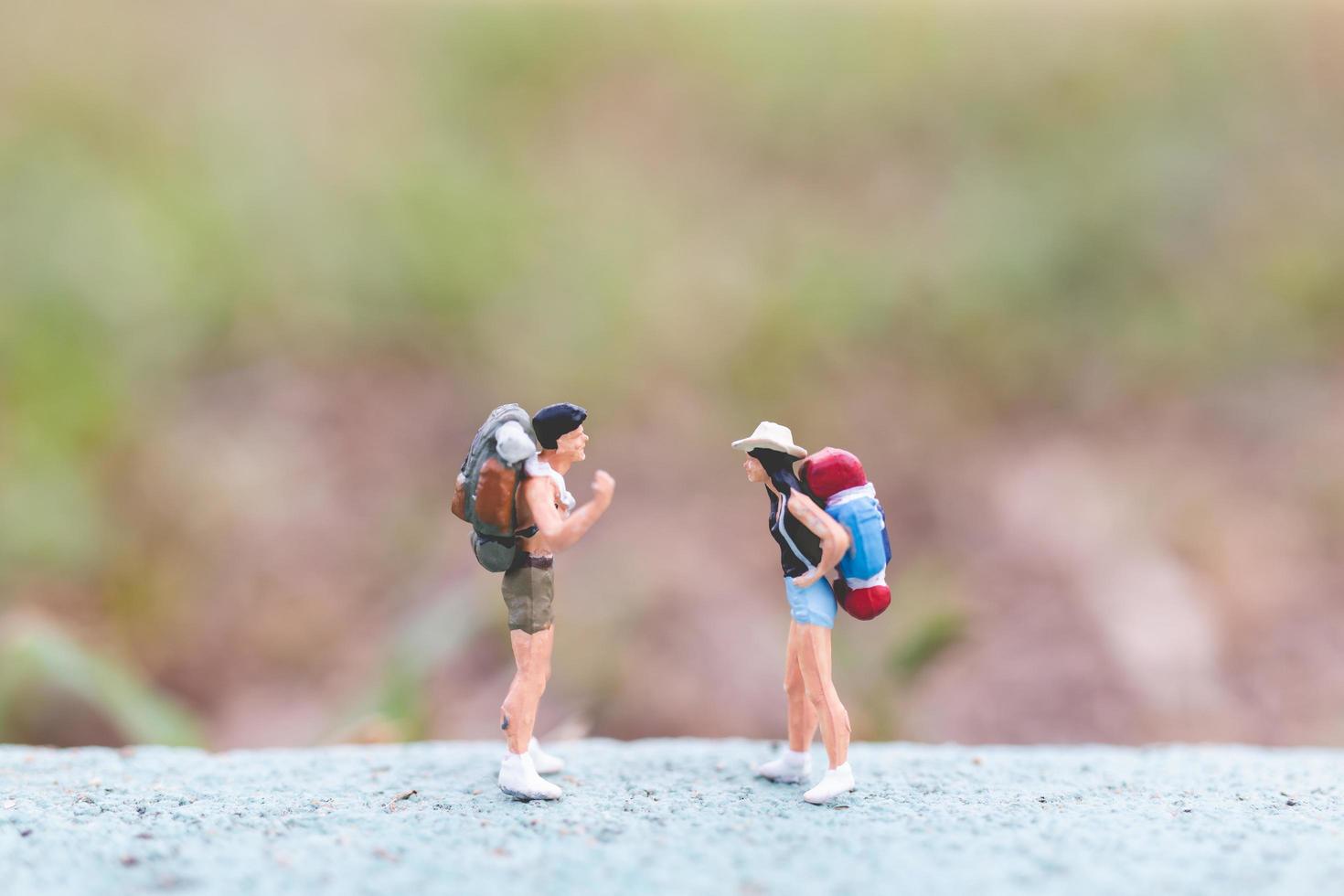 Miniaturreisende mit Rucksäcken, die auf einer Straße stehen, Reise- und Trekkingkonzept foto