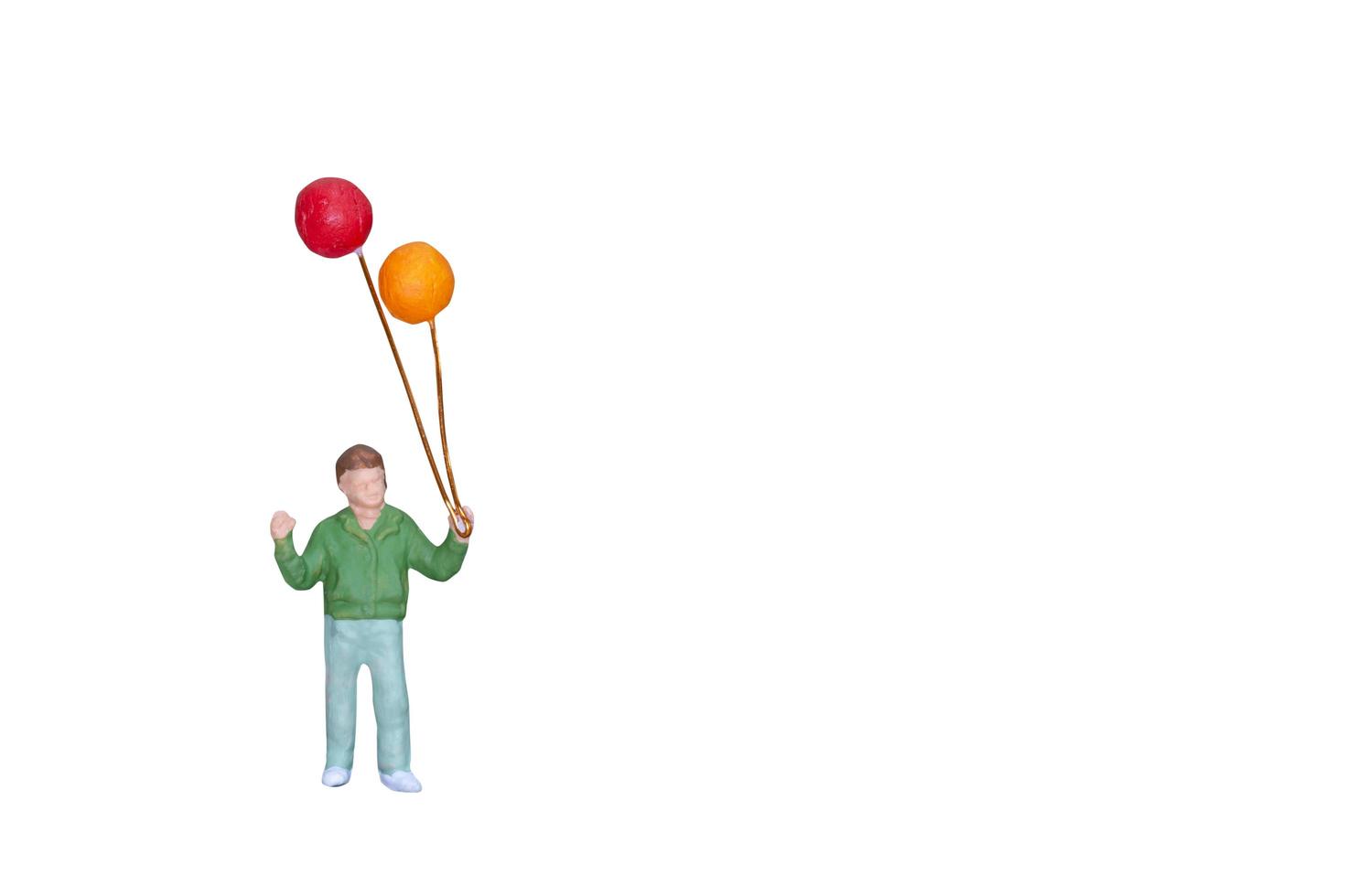 Miniaturperson, die Ballons lokalisiert auf einem weißen Hintergrund hält foto