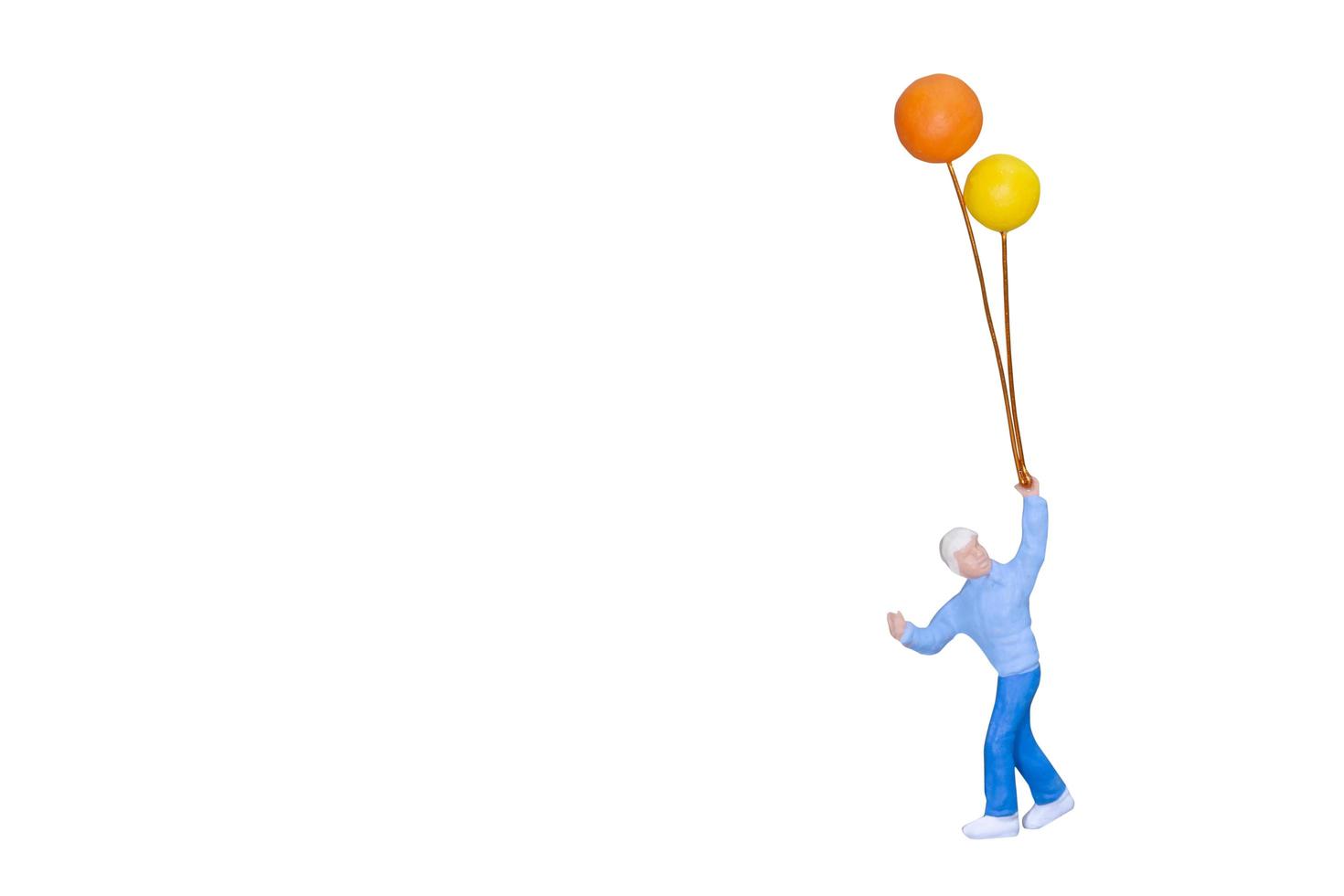 Miniaturperson, die Ballons lokalisiert auf einem weißen Hintergrund hält foto