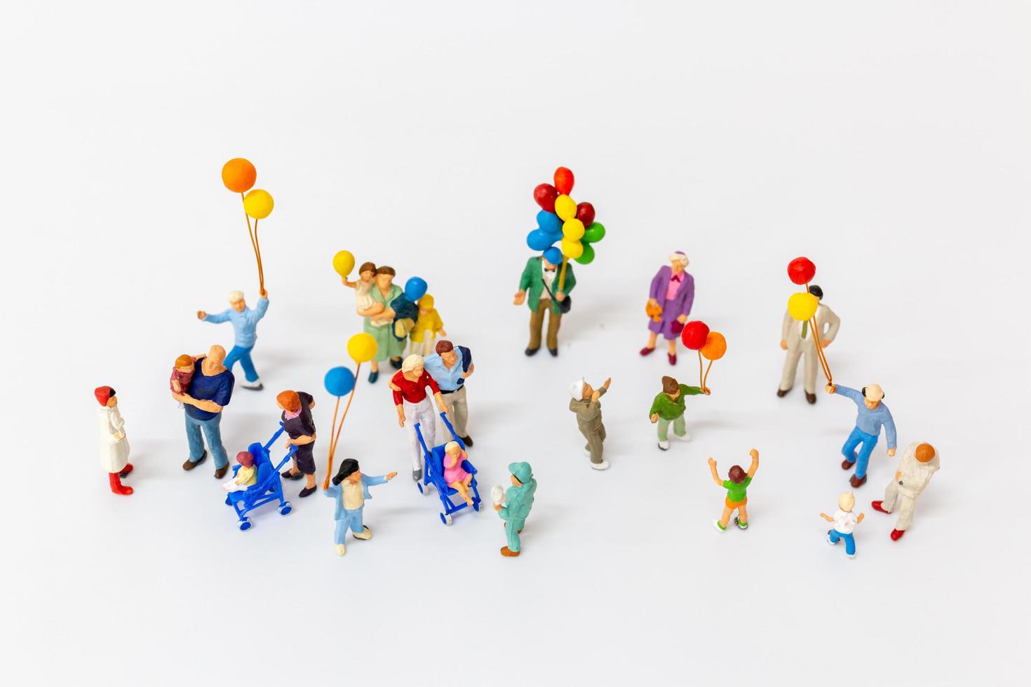 Miniaturleute, die Luftballons lokalisiert auf einem weißen Hintergrund halten foto