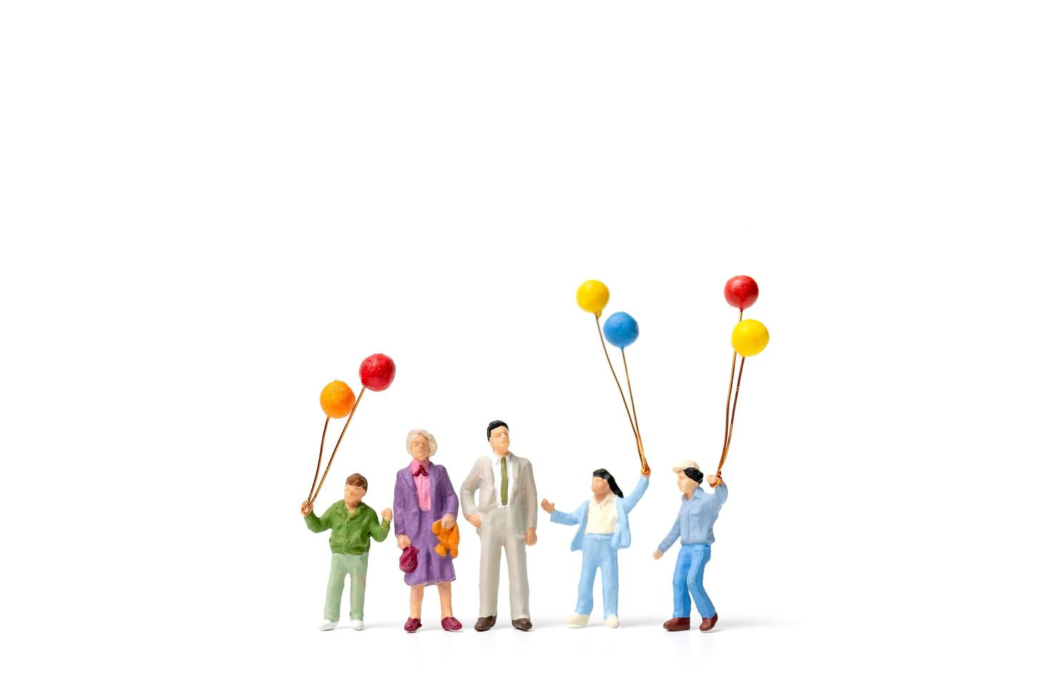 Miniaturleute, die Luftballons lokalisiert auf einem weißen Hintergrund halten foto