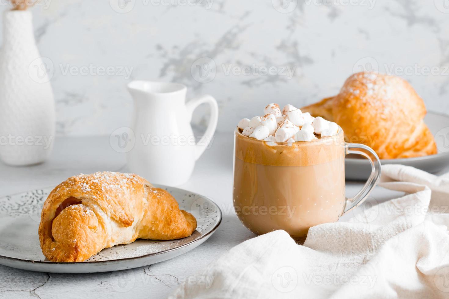 frisch Croissant auf ein Teller und ein groß Tasse von Kaffee auf das Tisch. hausgemacht Frühstück Lebensstil foto