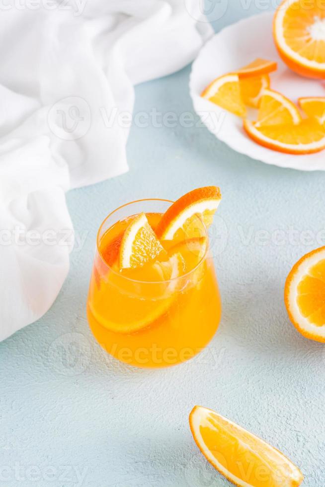 schwer Selters mit Kohlensäure Orange Cocktail mit Eis im Glas auf das Tisch. hausgemacht trinken. Vertikale Aussicht foto