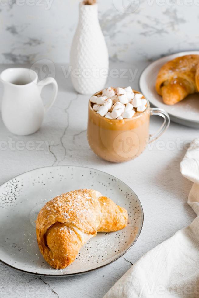 frisch Croissant auf ein Teller und ein groß Tasse von Kaffee auf das Tisch. hausgemacht Frühstück Lebensstil. Vertikale Aussicht foto