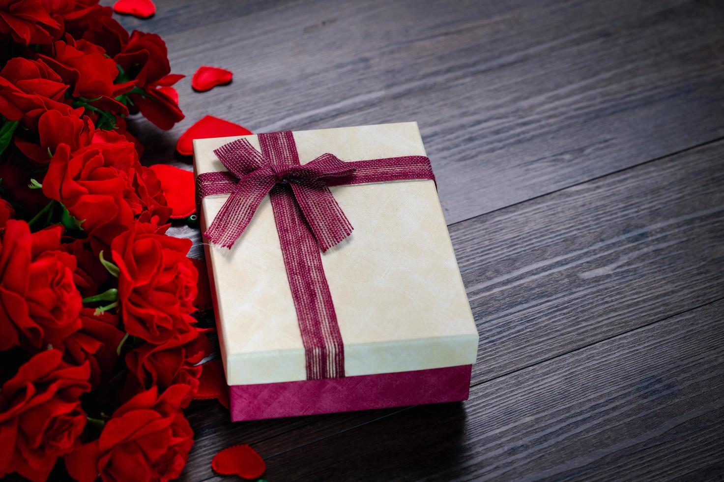 Geschenkbox und Rose auf hölzernem Hintergrund foto